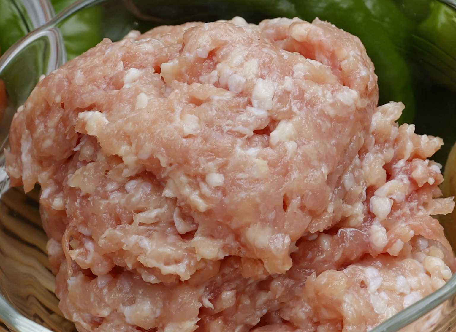 玻璃碗中的碎肉，背景有绿色蔬菜