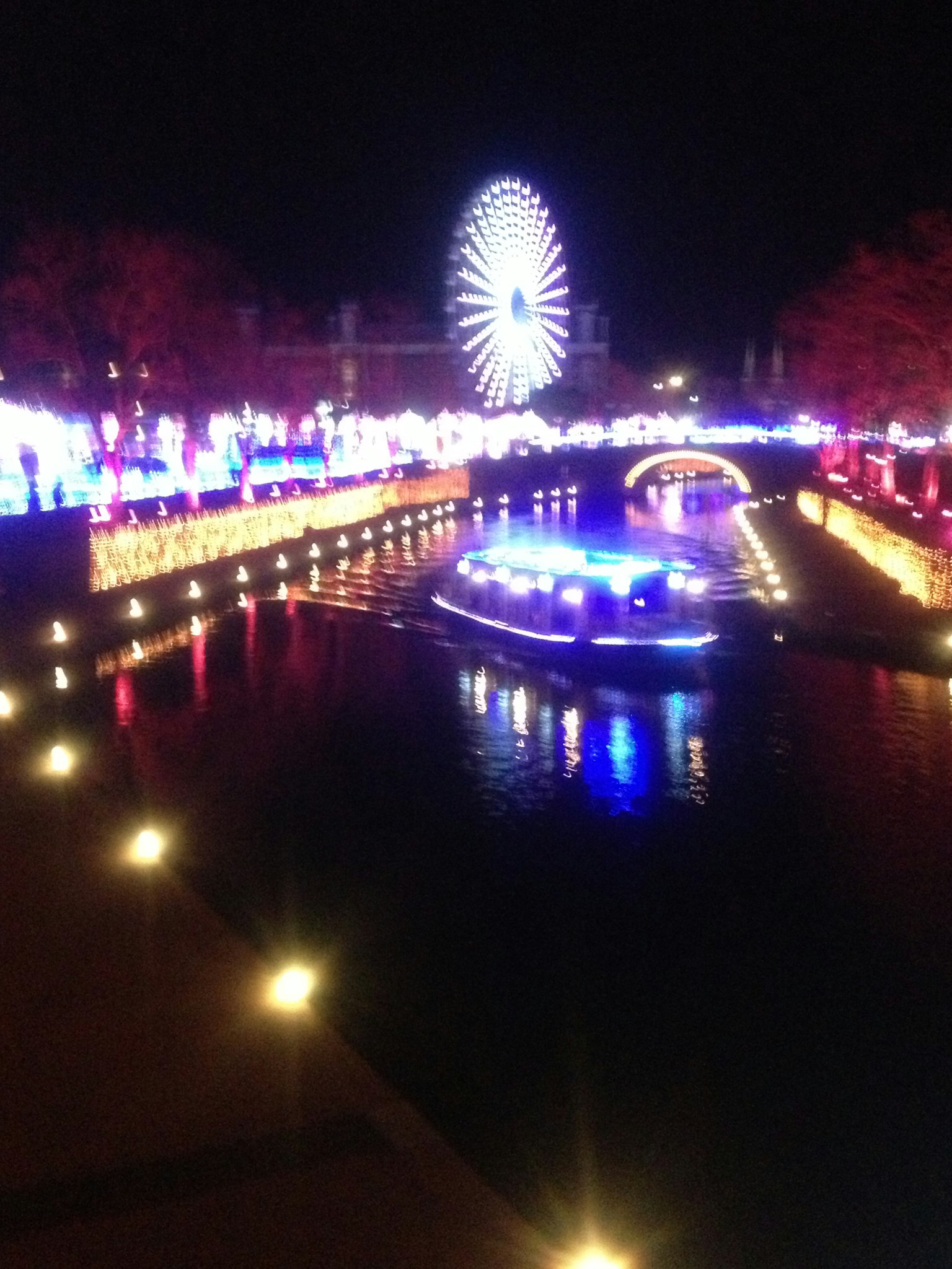 Bunte Lichter, die sich nachts im Fluss spiegeln, mit einem Riesenrad