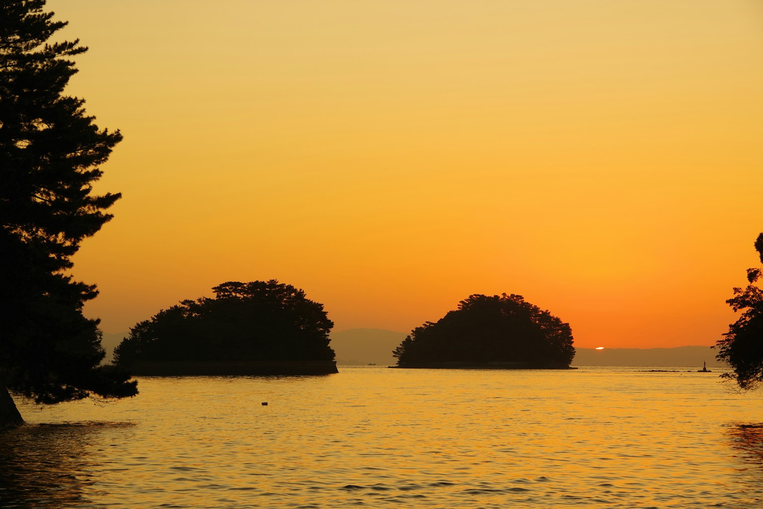 Landschaft mit Inseln bei Sonnenuntergang über ruhigem Wasser