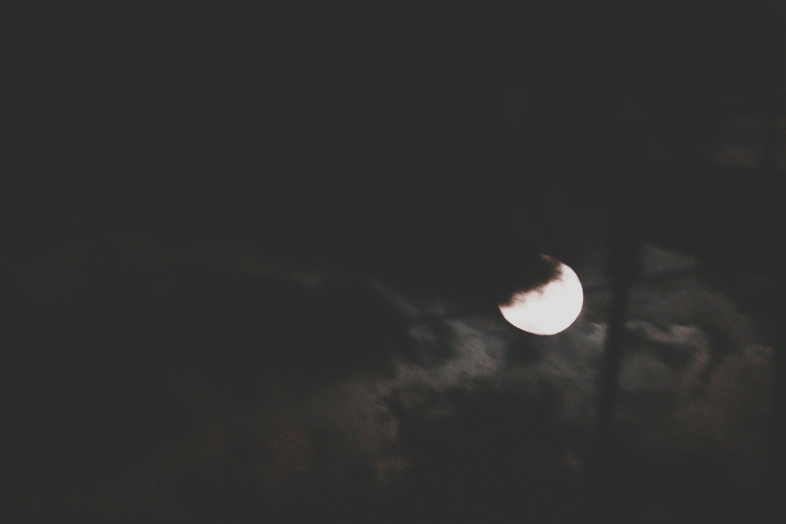 Luna parzialmente nascosta da nuvole in un cielo scuro