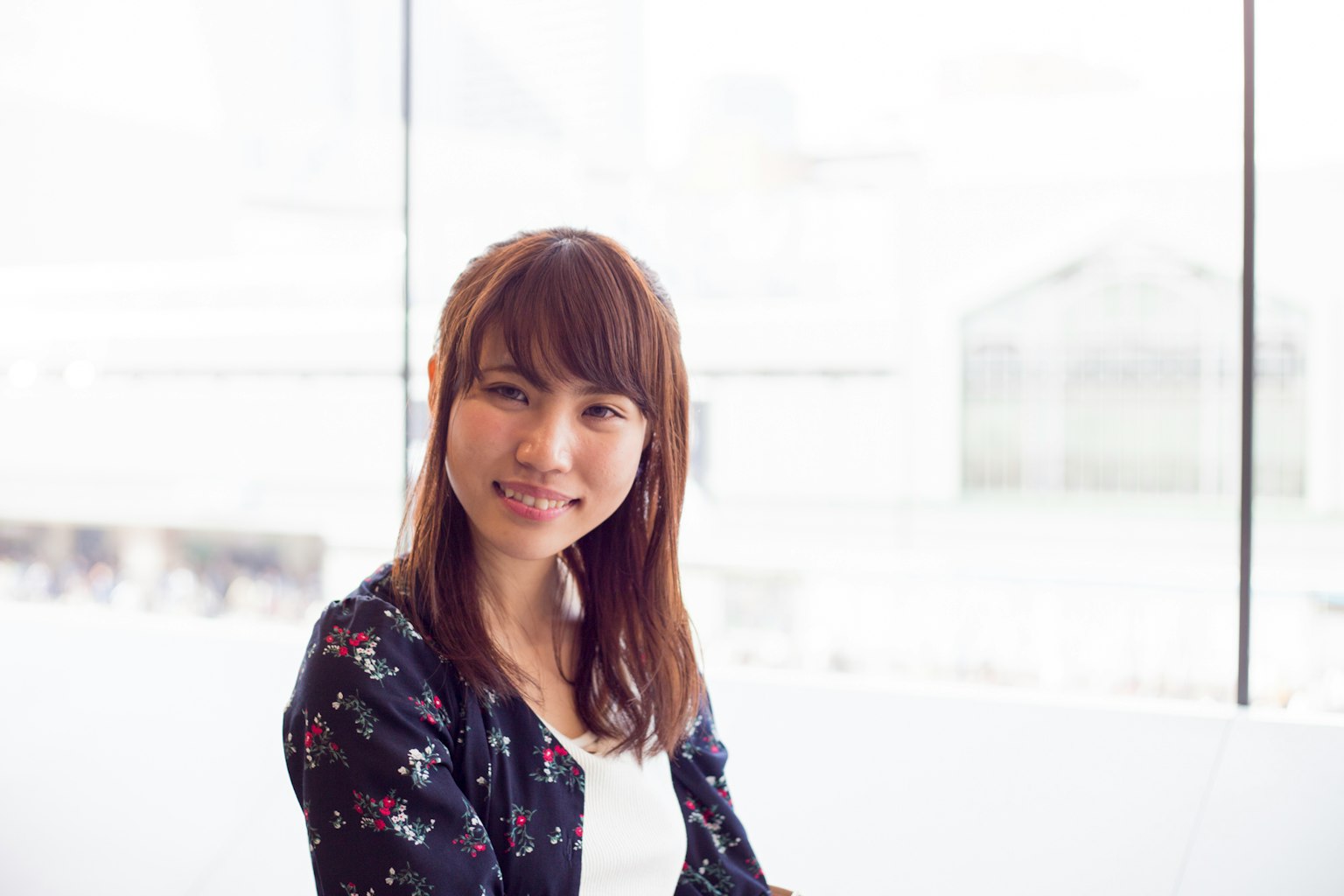 Retrato de una joven sonriente sentada junto a una ventana