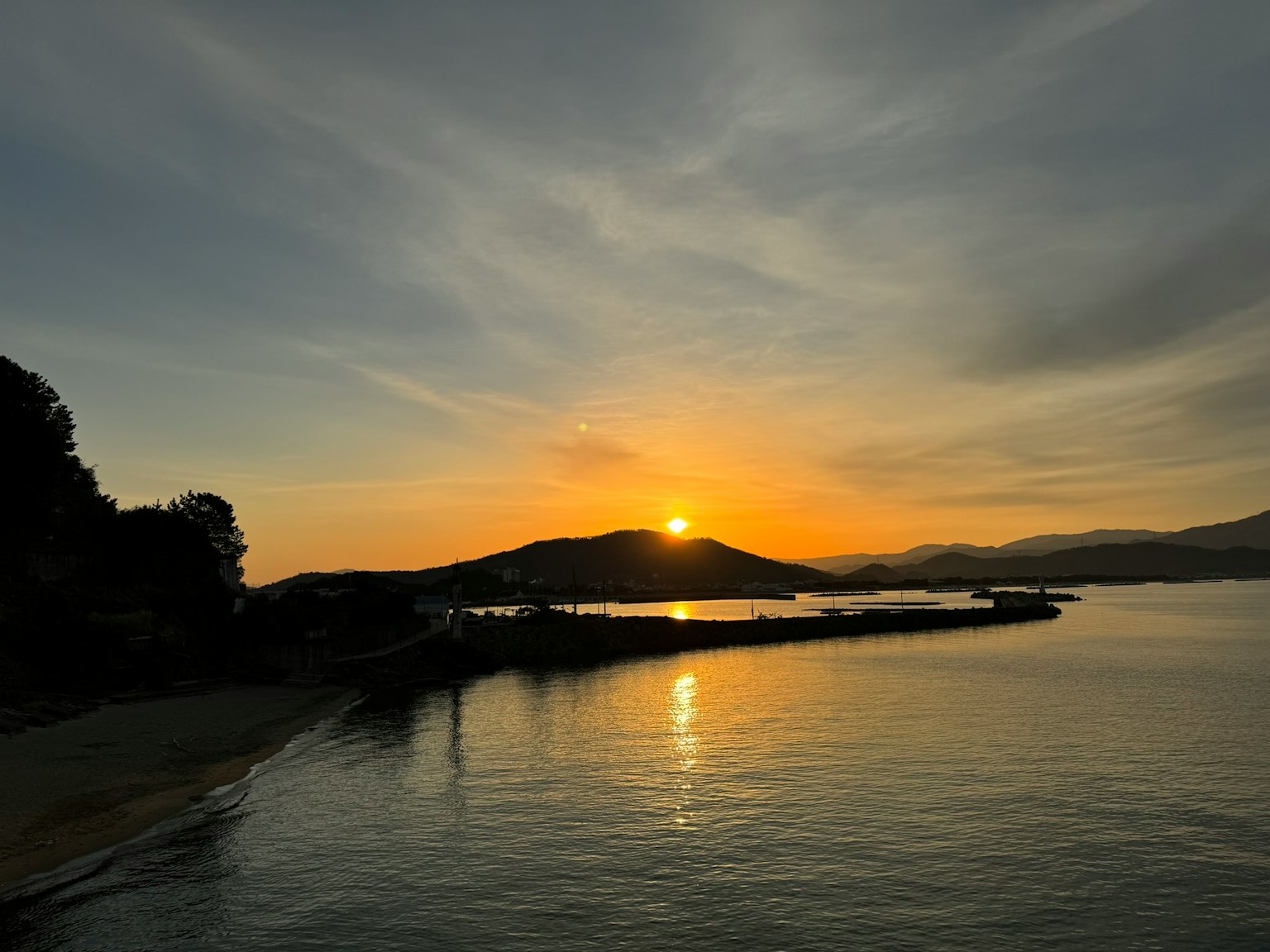 夕日が海に沈む美しい風景 浜辺と山が見える