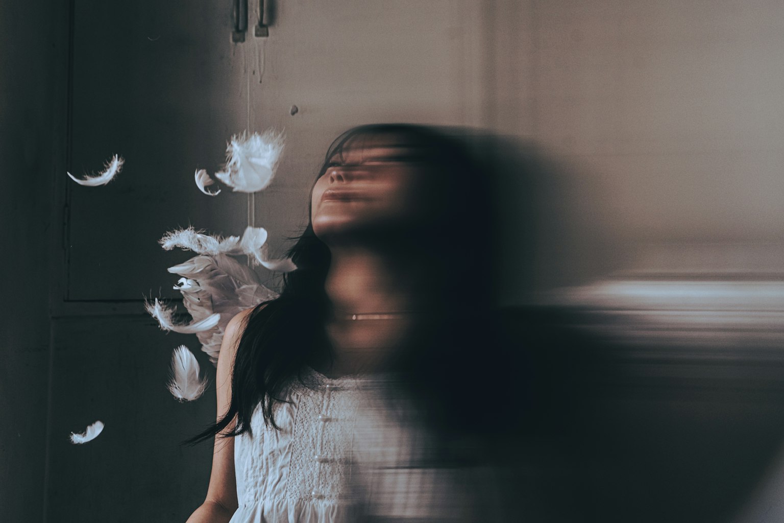 羽毛が舞う中で動く女性の姿
