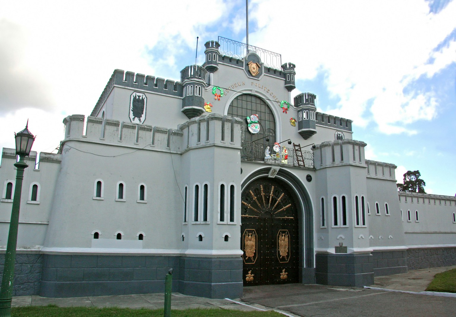 Exterior de un castillo gris con una gran puerta dorada y un diseño decorativo