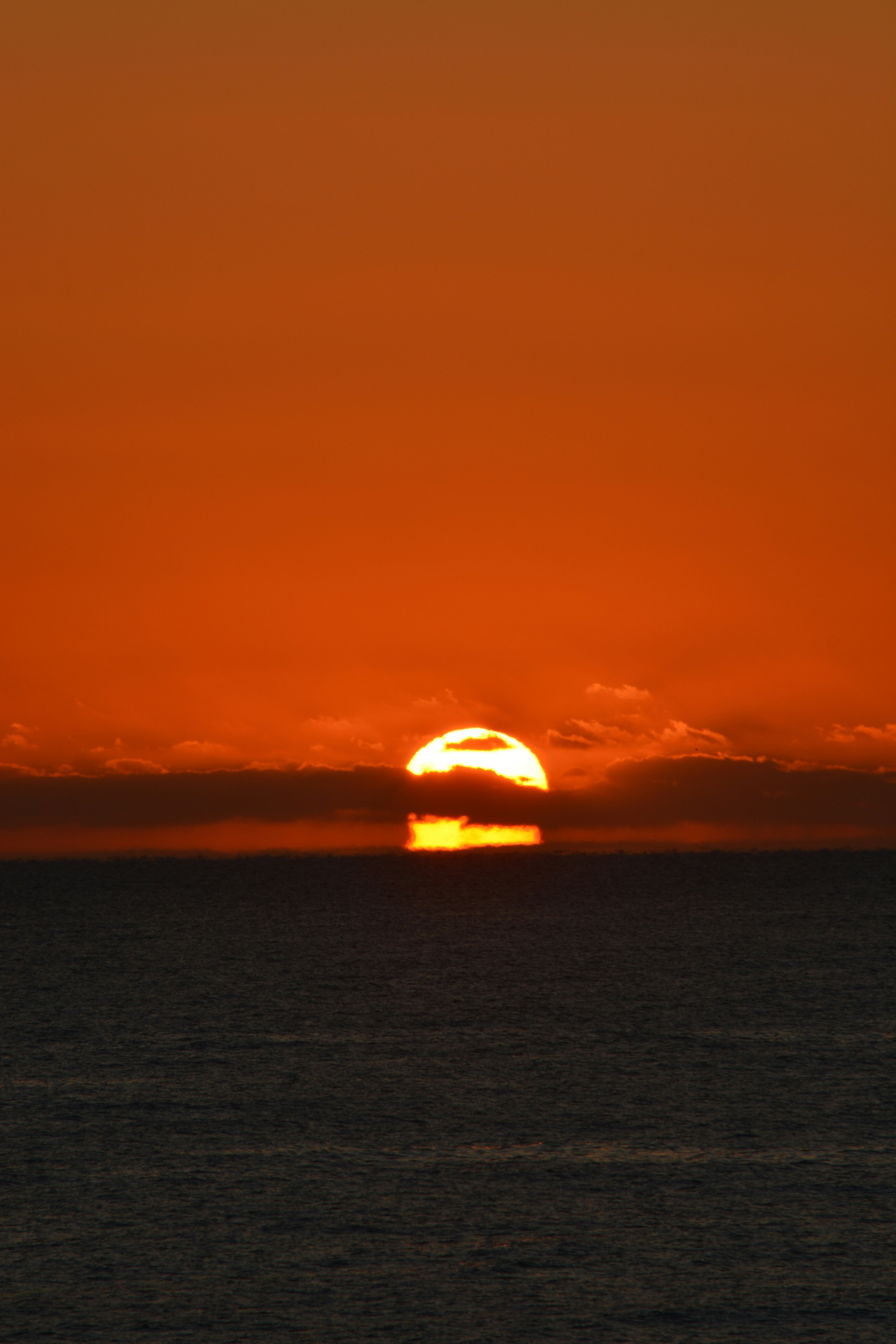 冬の海に沈む夕日と赤い空