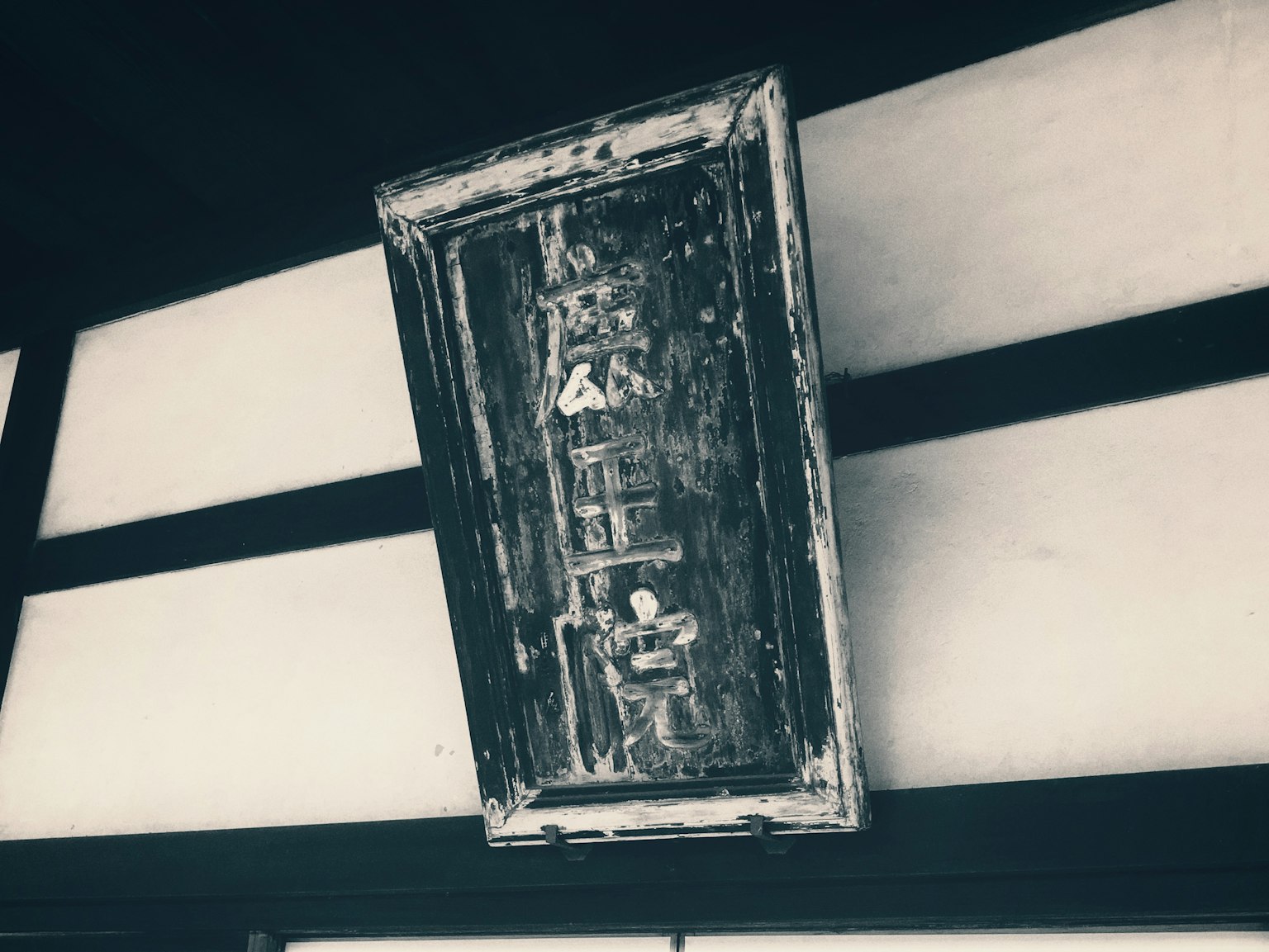 Ein altes Holzschild, das von der Decke hängt