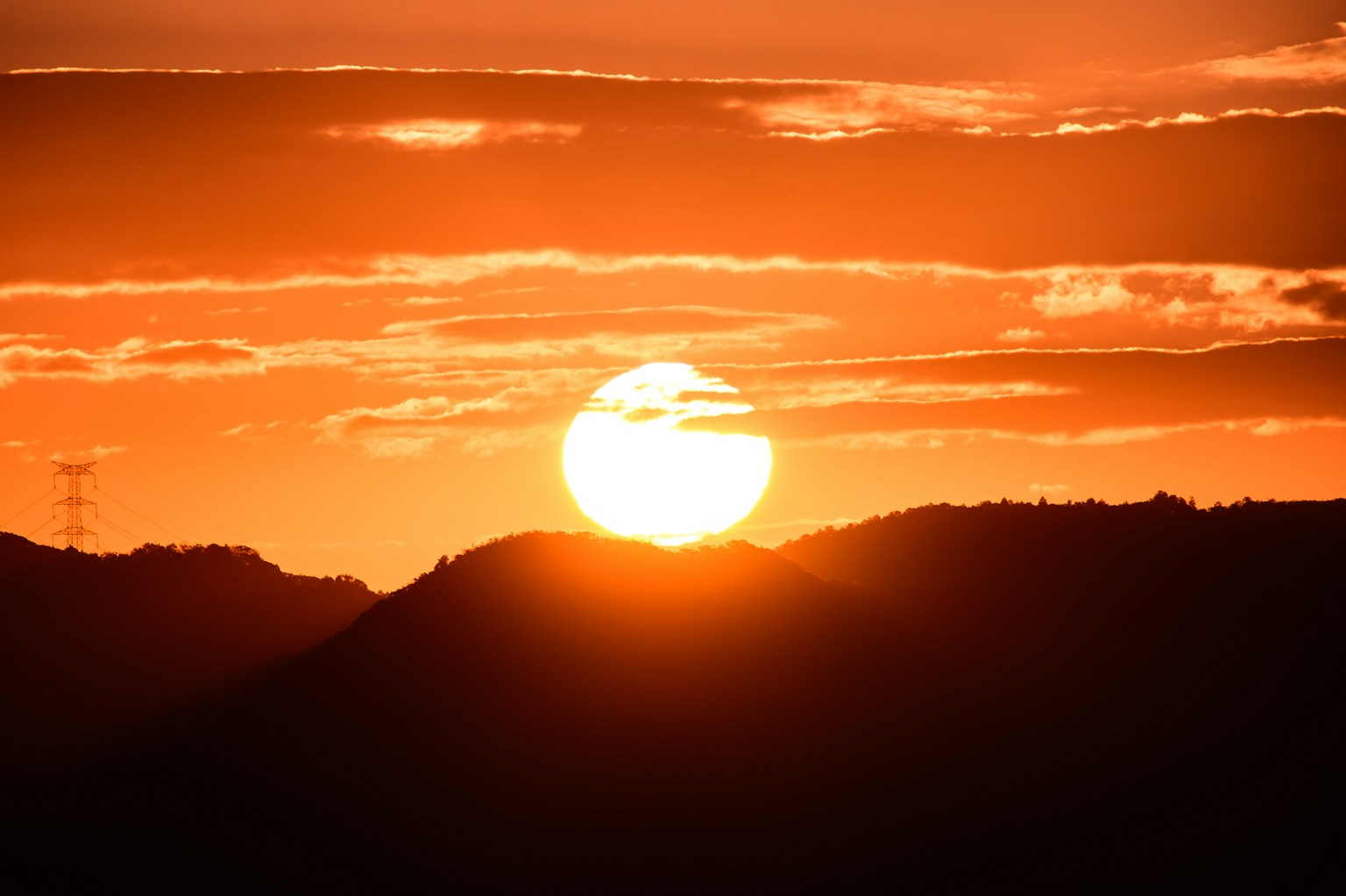Silhouette matahari terbenam yang indah di atas pegunungan dengan langit oranye