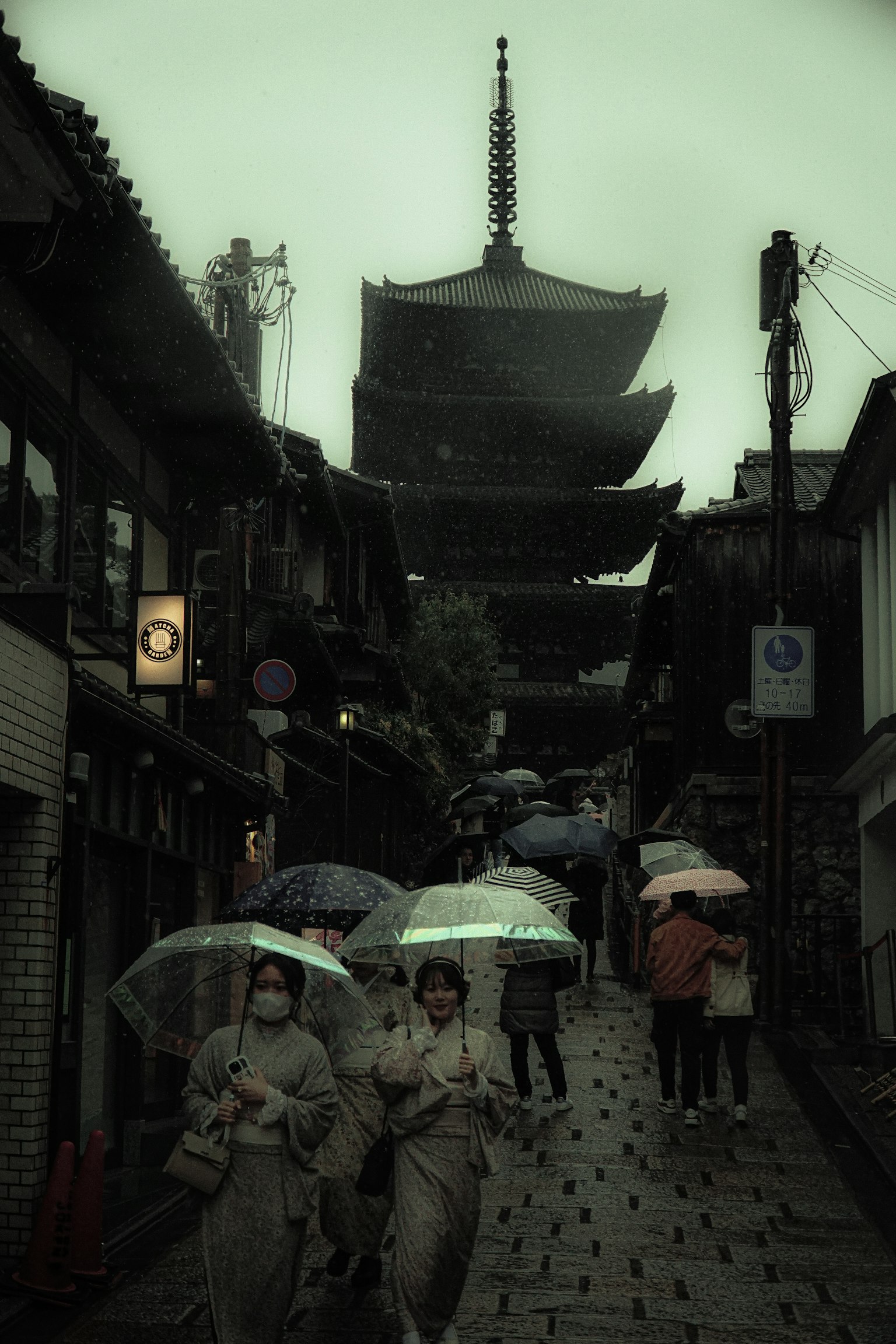 Des gens marchant sous la pluie avec des parapluies près d'une pagode dans une vieille rue