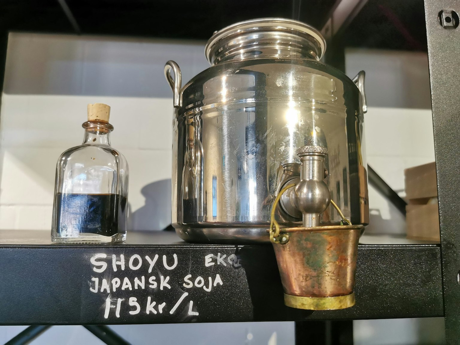 Un conteneur en acier inoxydable pour sauce soja et une bouteille en verre sur une étagère
