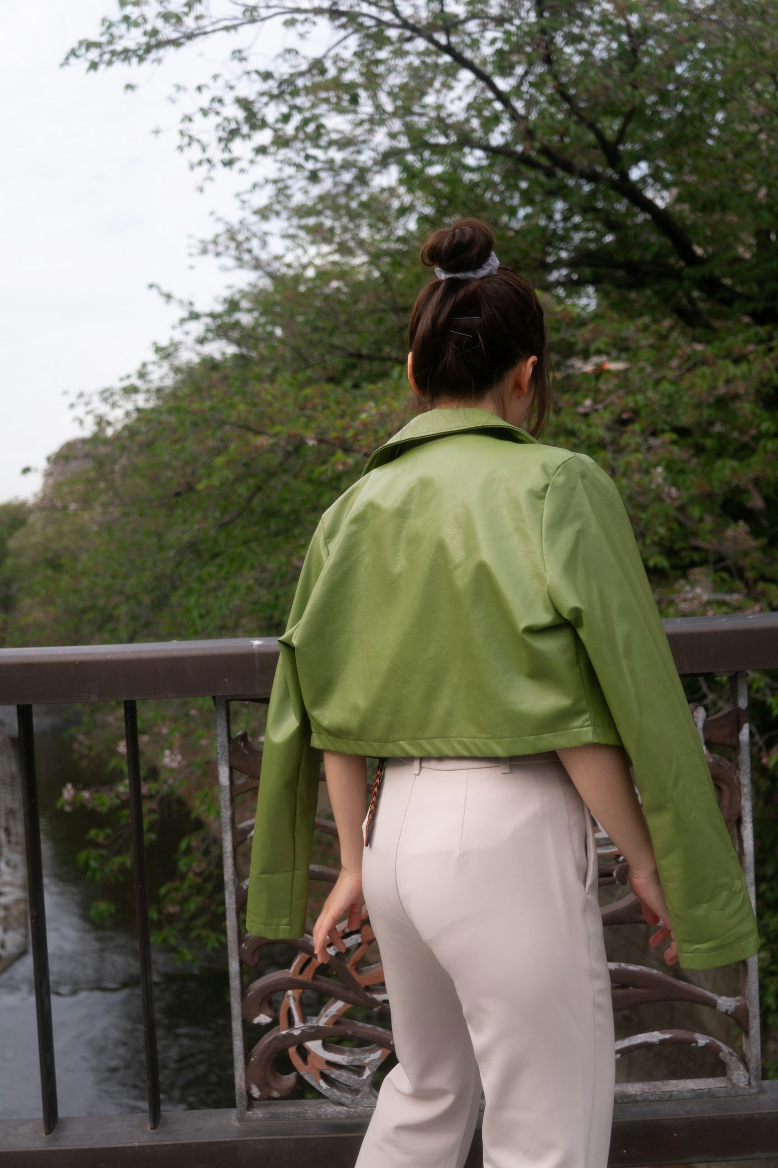 Woman wearing a green jacket standing by a river