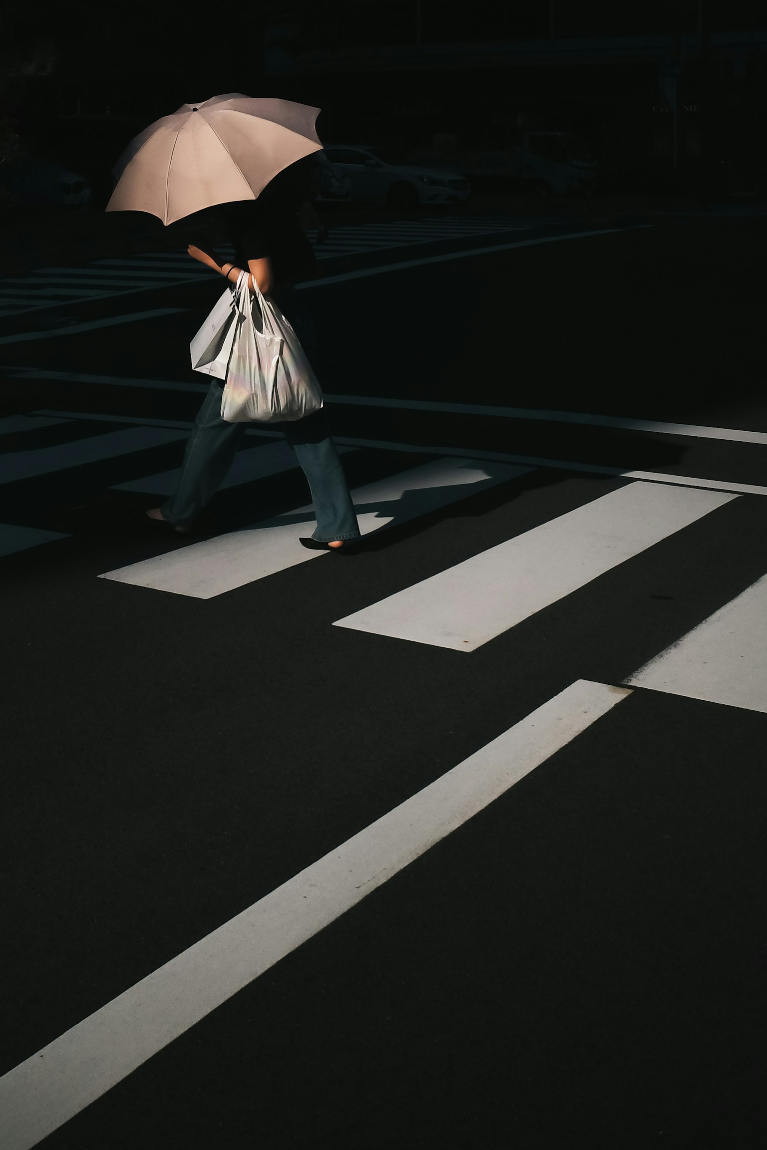 傘を持って横断歩道を渡る人影