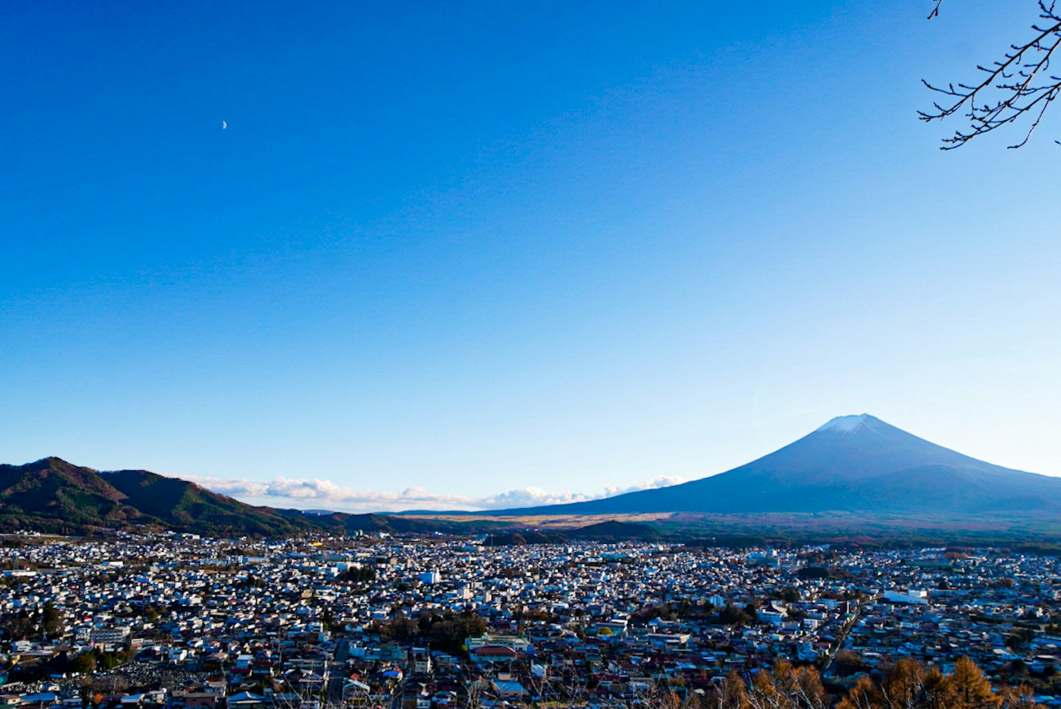 Blick auf den Fuji unter einem klaren blauen Himmel mit einer Stadtlandschaft