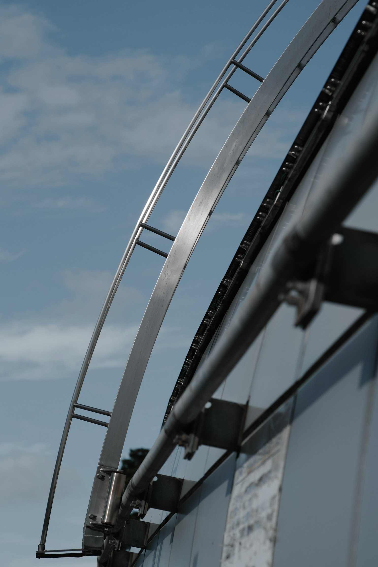 Structure métallique courbée contre un ciel bleu avec des nuages
