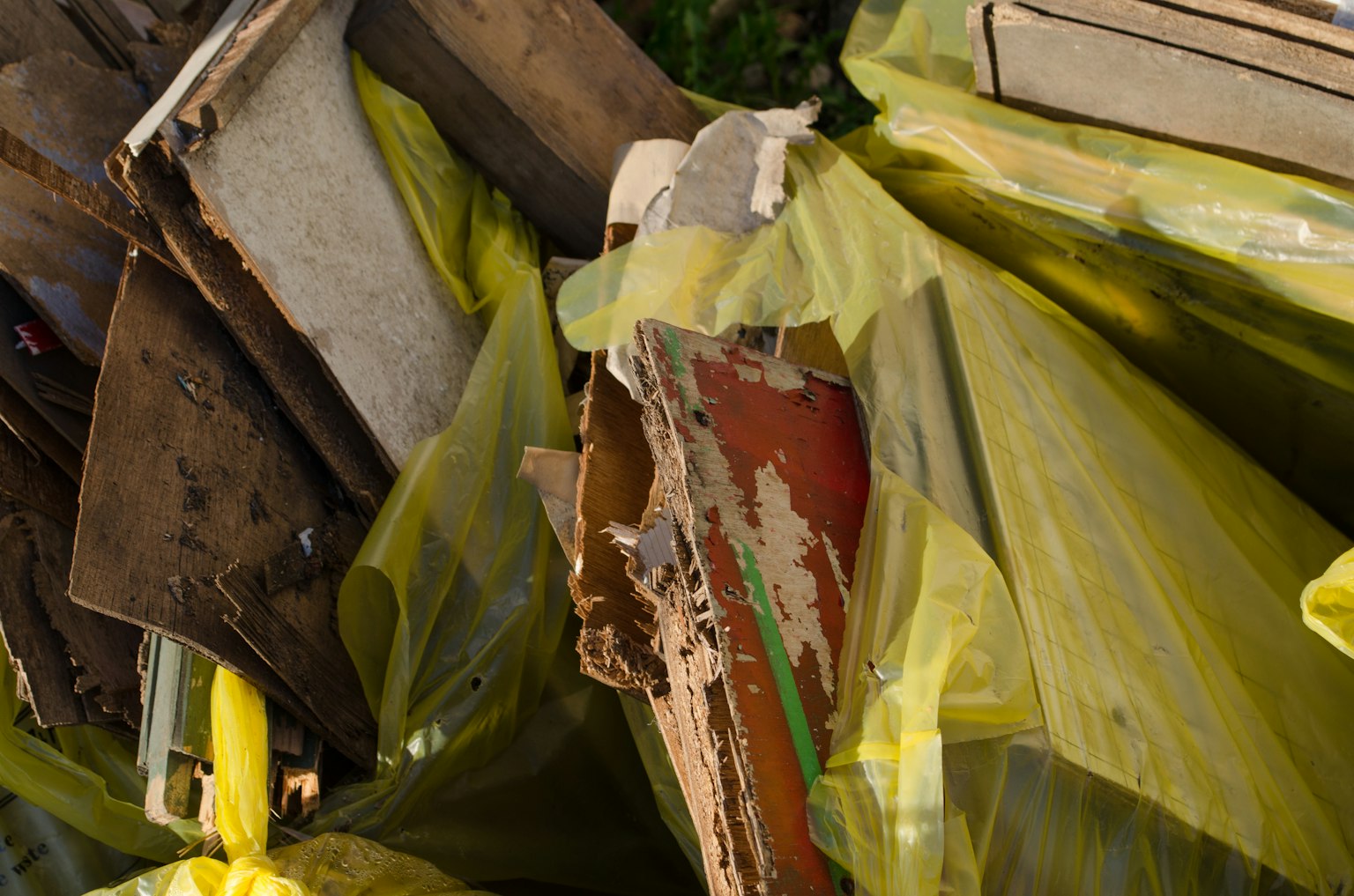 Débris en bois cassé et sacs poubelles jaune-vert empilés ensemble
