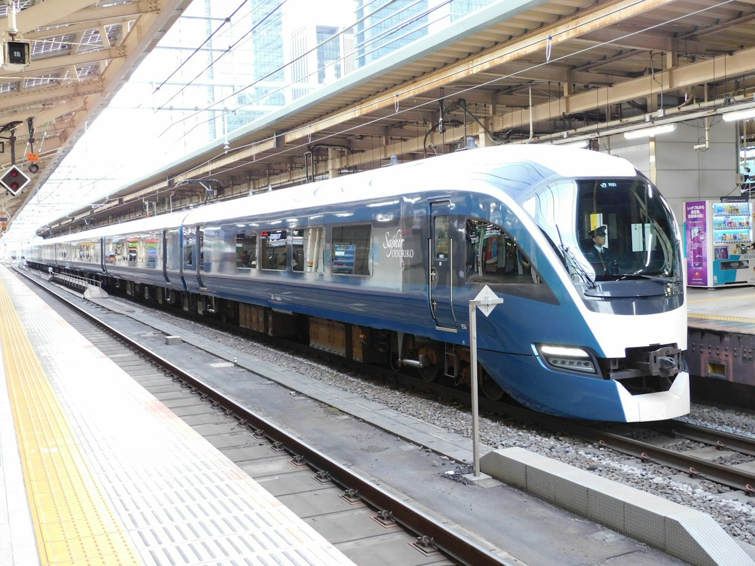 A modern blue and white train is stopped at a station