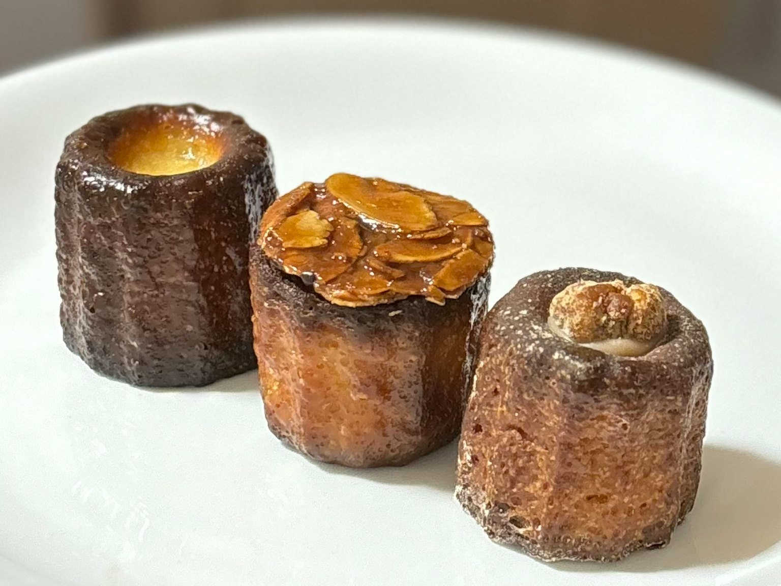 Three canelés displayed on a white plate