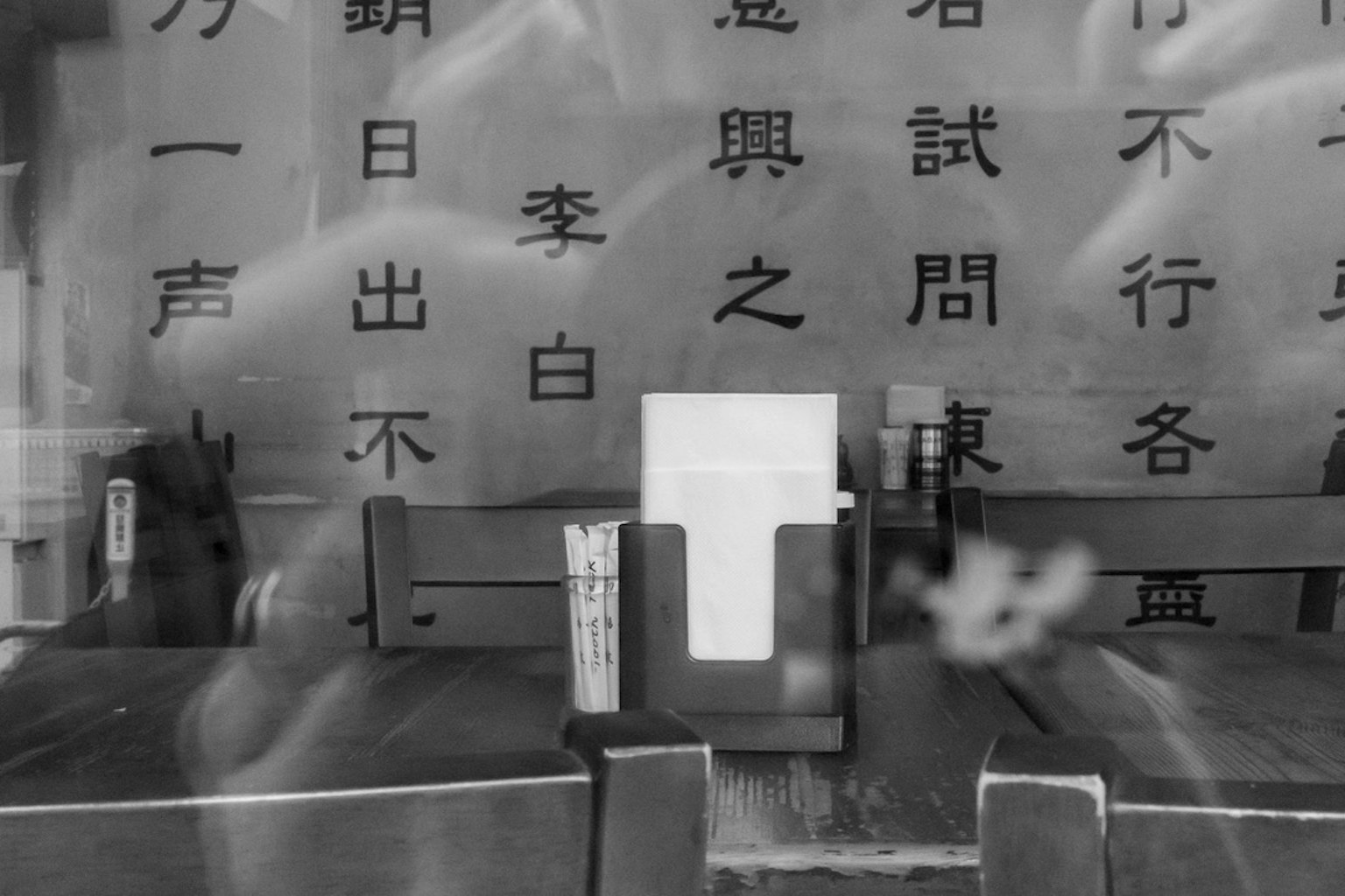 白色菜單放置在木桌上，背景是黑色字符的牆