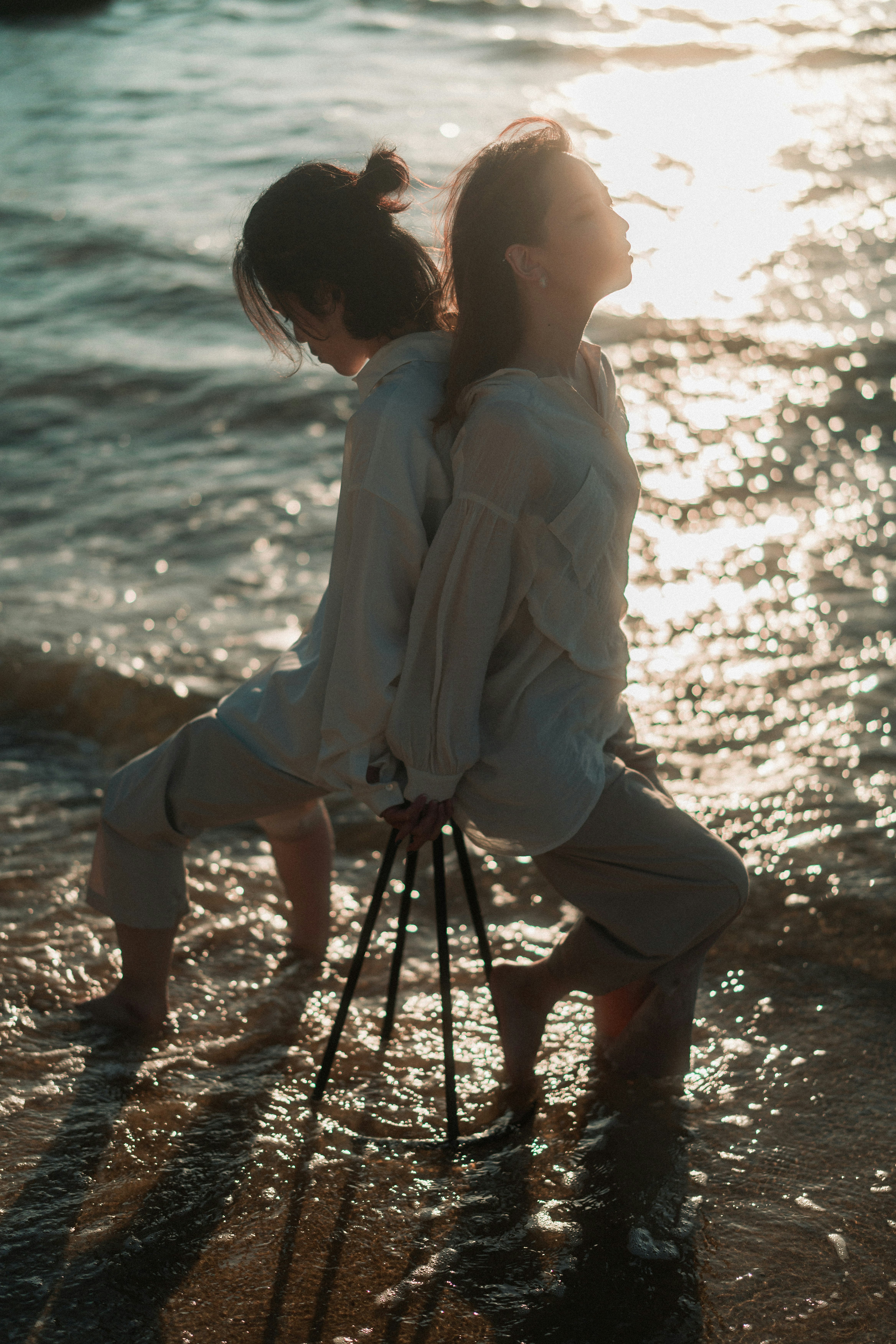 夕暮れの海辺で寄り添うカップルの後ろ姿
