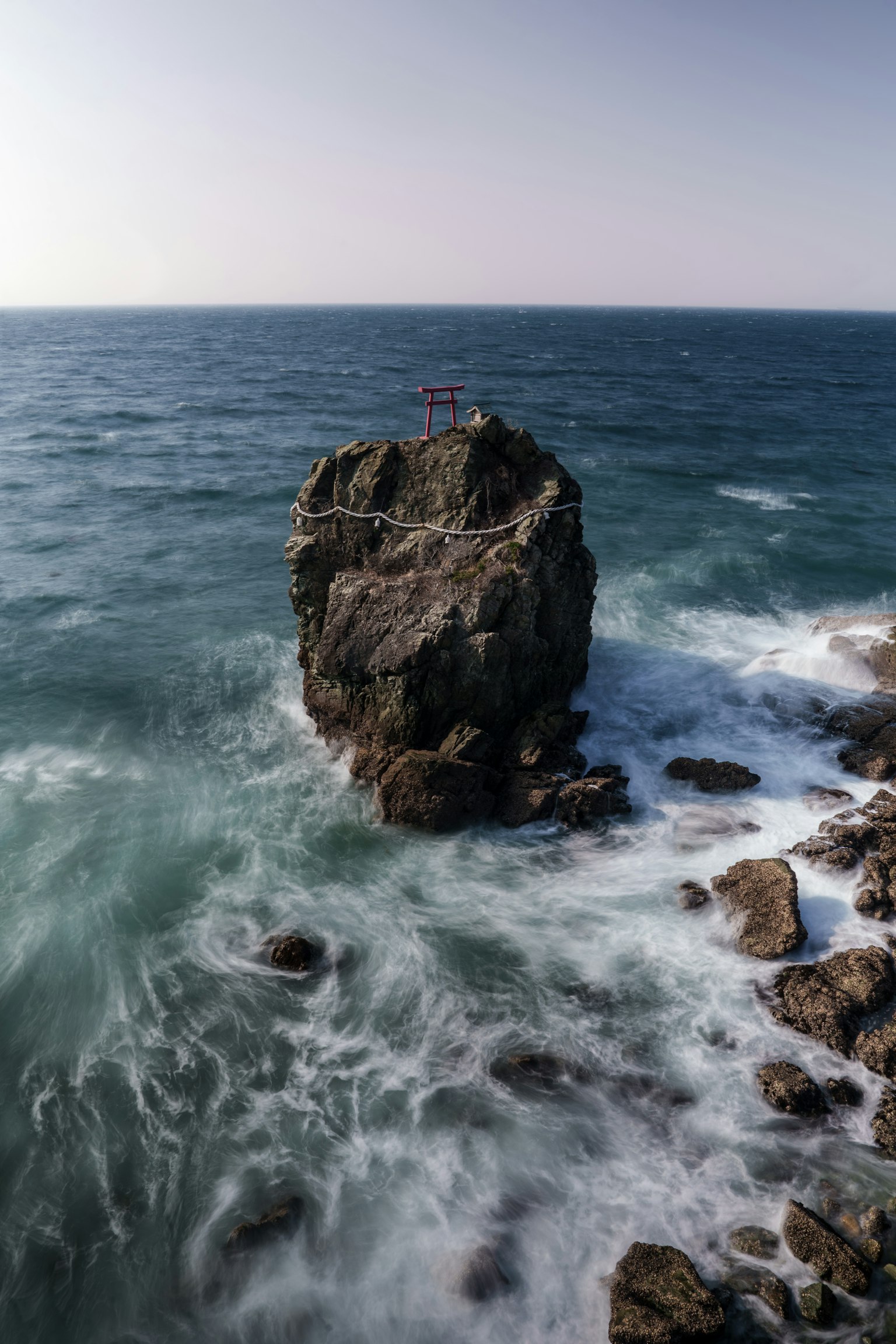 Un grand rocher entouré de vagues océaniques bleues
