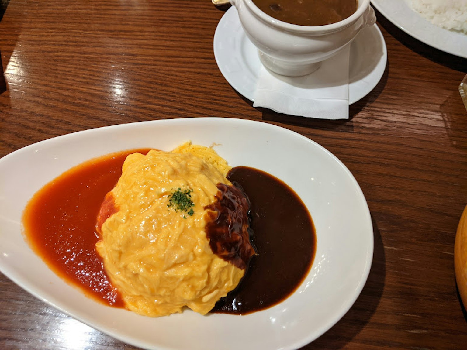 Teller mit Omelettreis, garniert mit roter Tomatensauce und brauner Demi-Glace-Sauce