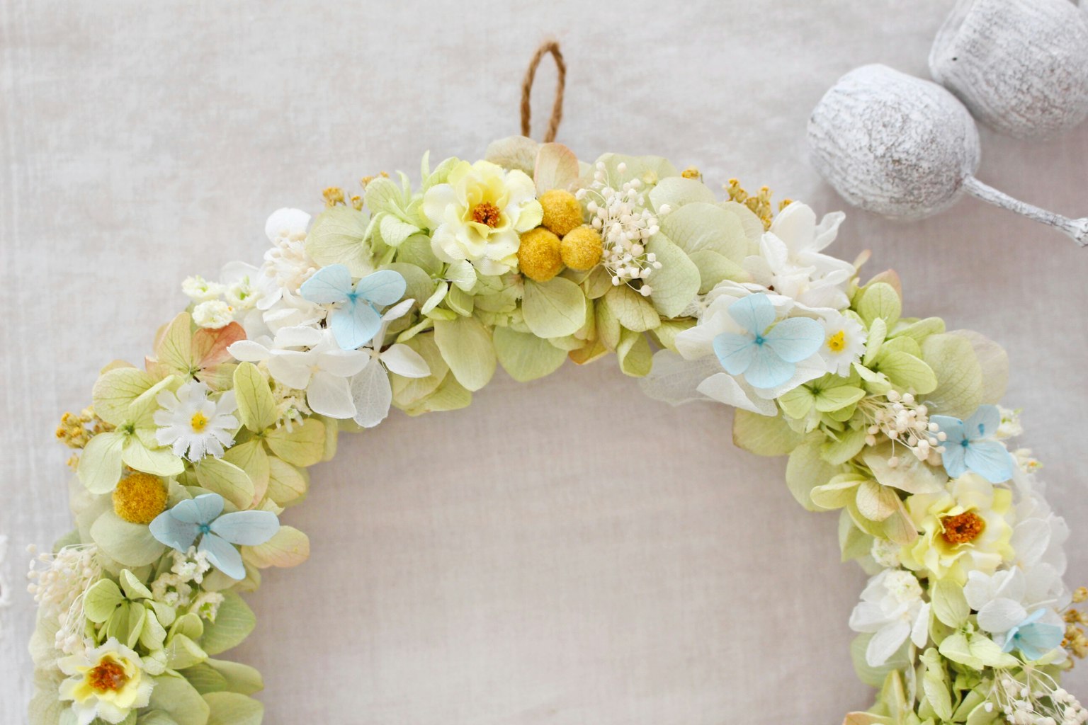 Ein Blumenkranz geschmückt mit pastellfarbenen Blumen und weißen Dekorationen