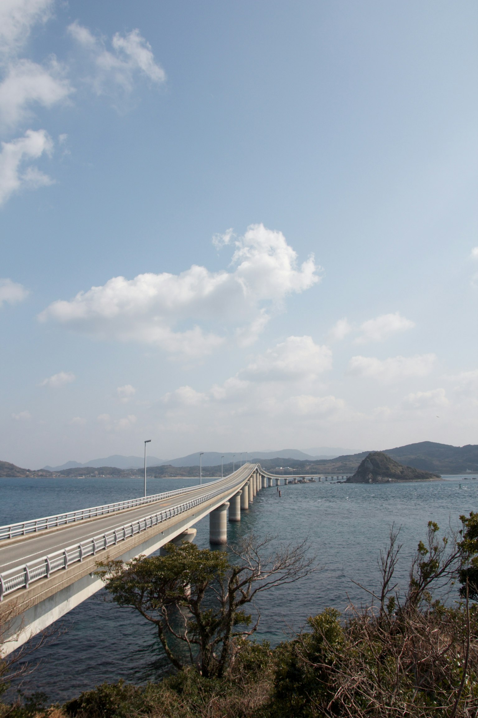 Un pont s'étendant sur l'eau sous un ciel bleu avec des nuages