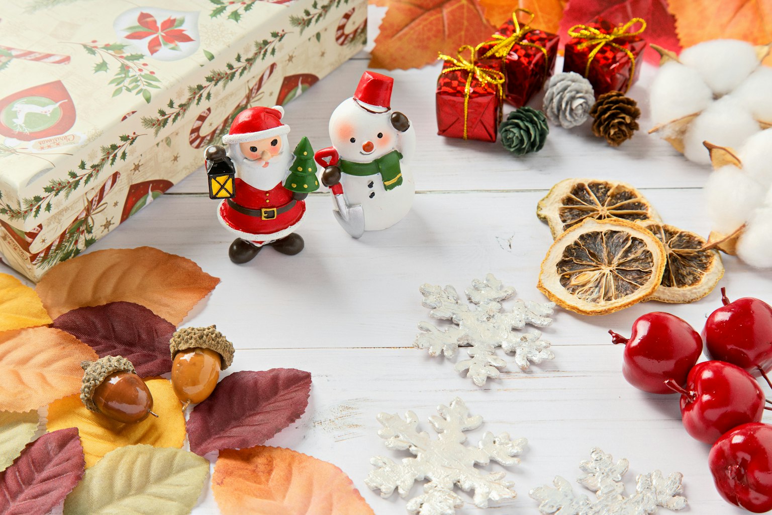 Adegan dekoratif dengan patung Santa Claus dan manusia salju daun musim gugur jeruk kering dan hadiah Natal