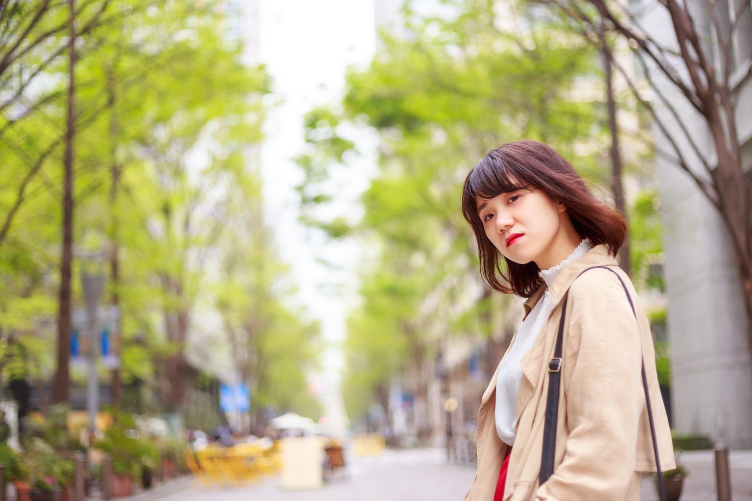Portrait of a woman smiling in a tree-lined urban street
