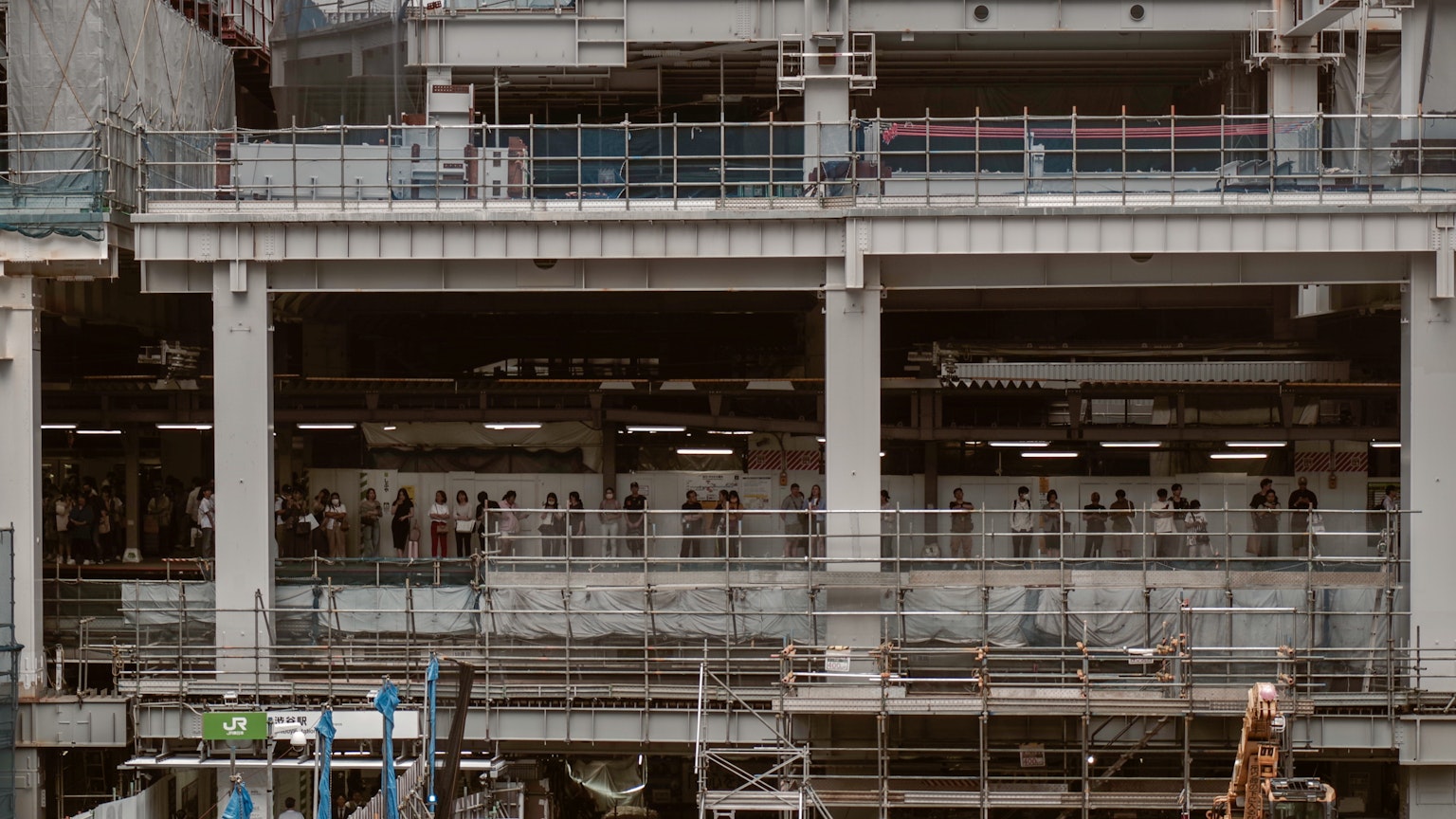 Gambar gedung yang sedang dibangun dengan beberapa pekerja terlihat