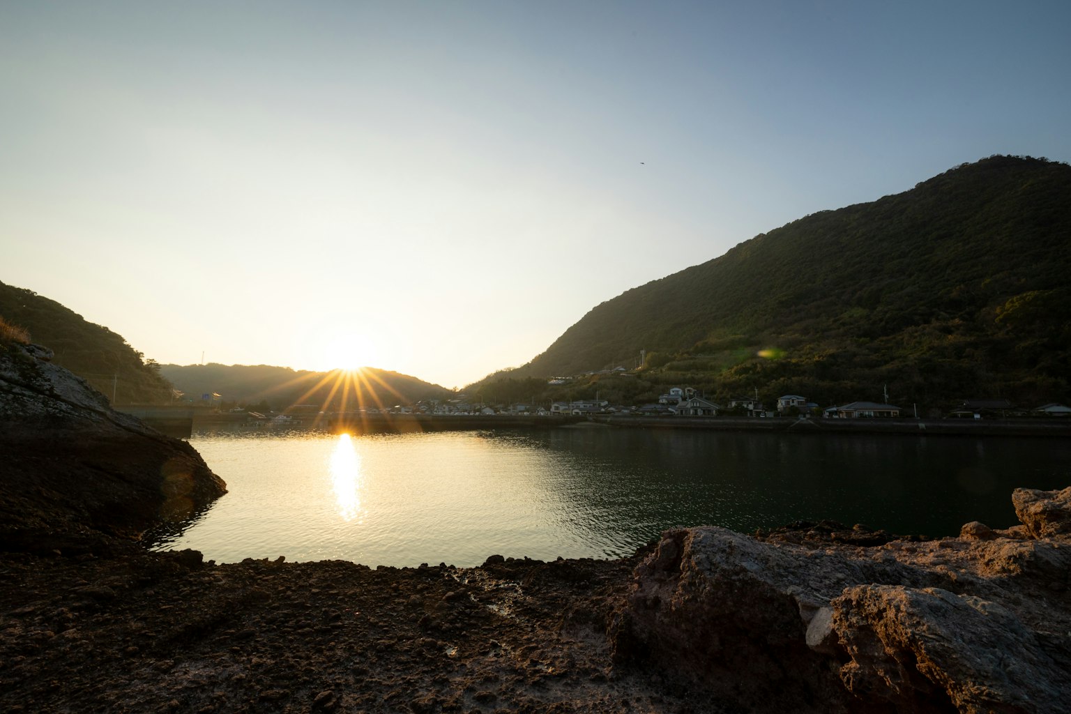 Sunset over a serene lake with mountains in the background