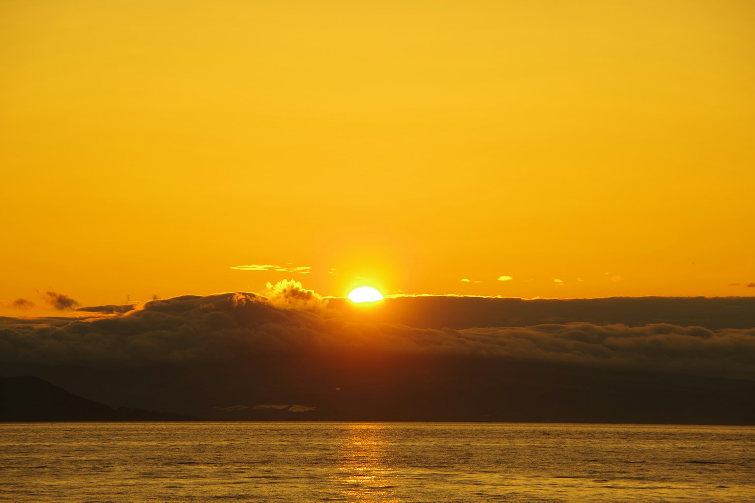 Un beau coucher de soleil sur la mer avec un ciel orange et des nuages