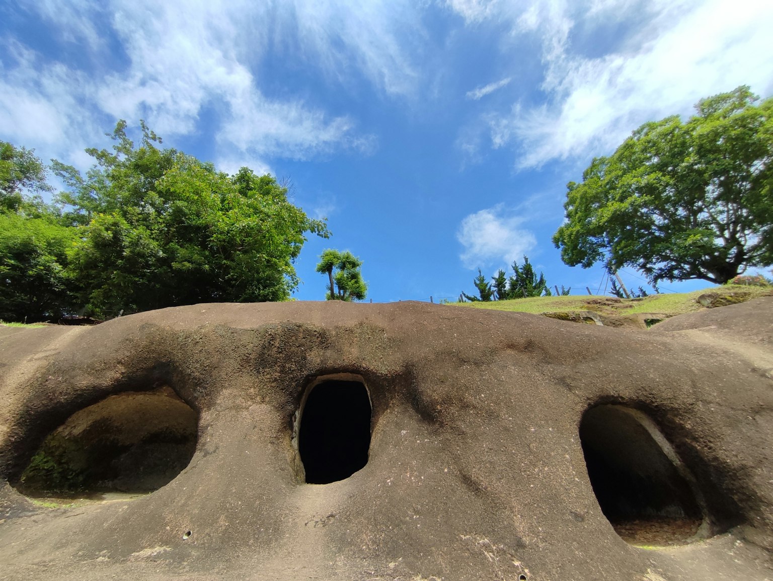 Paesaggio con grotte di roccia sotto un cielo blu e vegetazione
