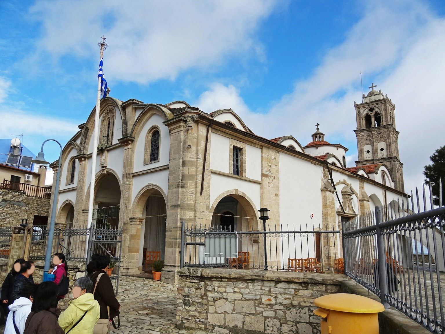 Chiesa storica con archi e un campanile sotto un cielo blu con turisti