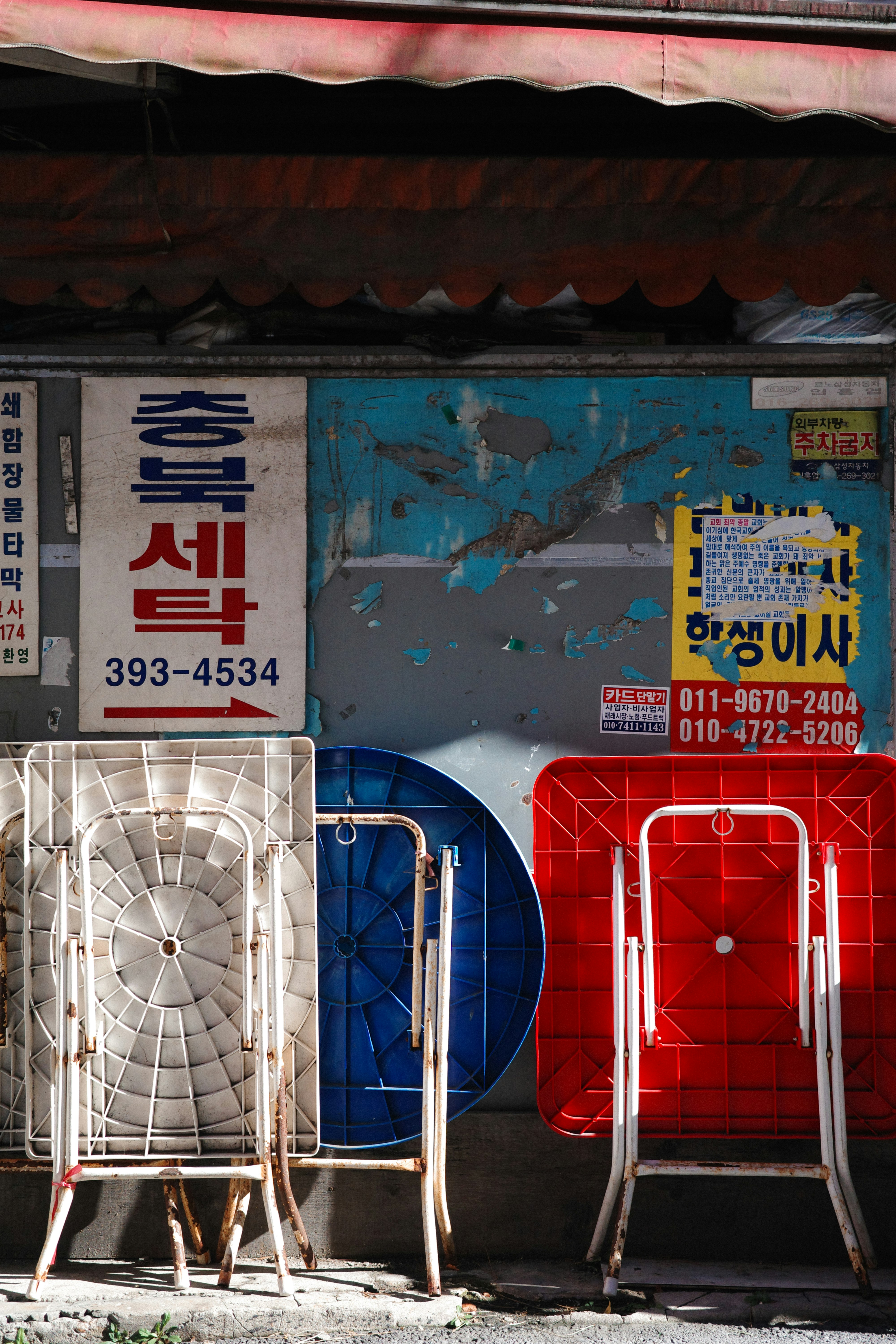 Außenansicht eines alten Geschäfts mit blauen und roten Tischen und koreanischen Beschilderungen an der Wand
