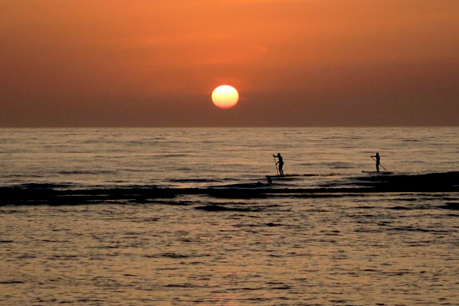 海边夕阳下站着两个人的剪影