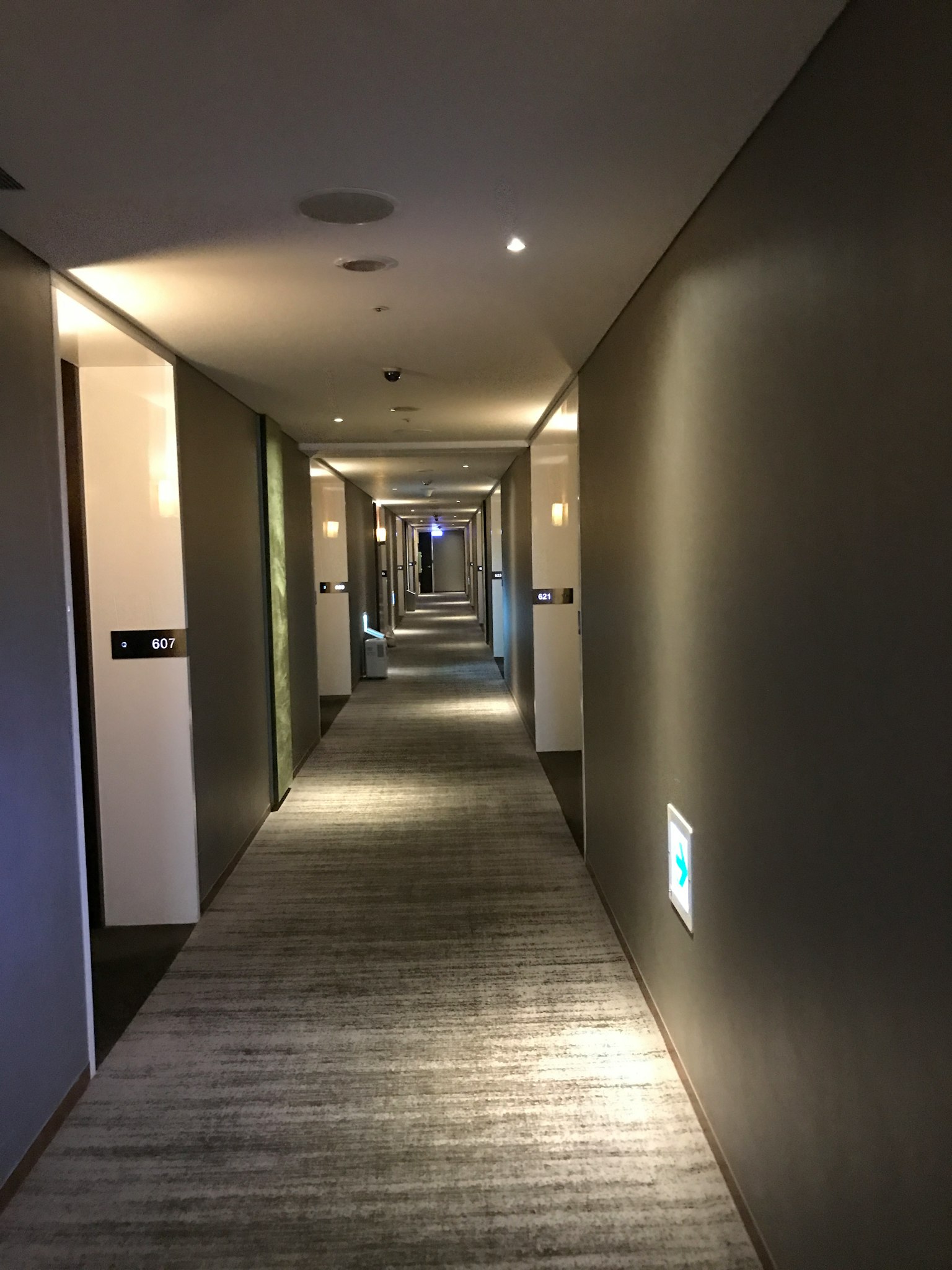 Ein langer Hotelflur mit gedämpfter Beleuchtung Moderne graue Wände und sanfte Beleuchtung schaffen eine beruhigende Atmosphäre