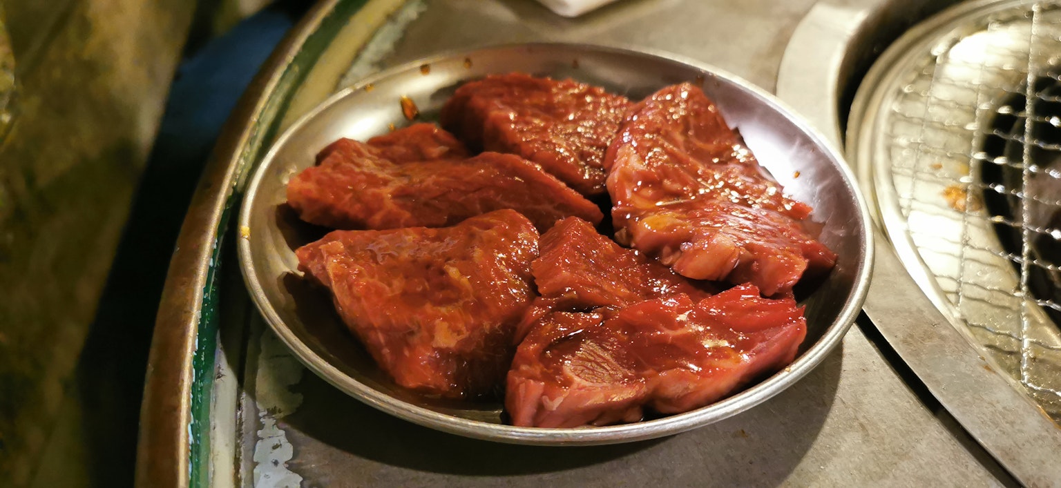 Un piatto di carne marinata accanto a una griglia