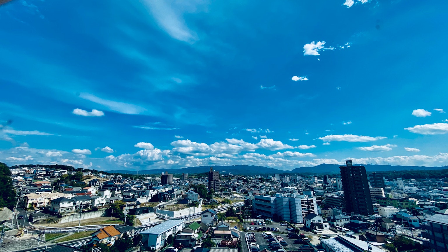 ทิวทัศน์พาโนรามาของเมืองที่มีท้องฟ้าสีฟ้าและเมฆ