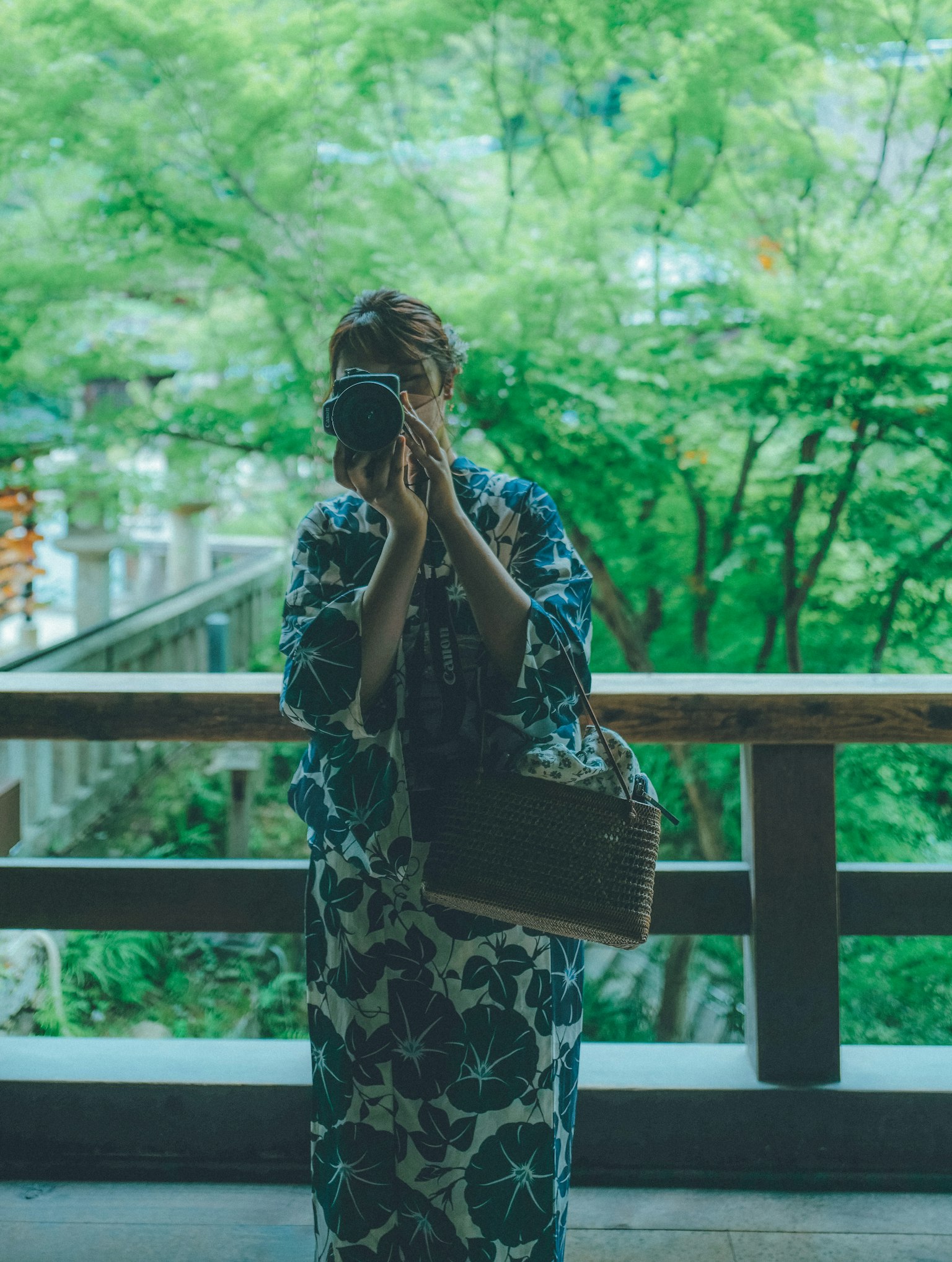 穿著和服的女性在綠色背景下拿著相機