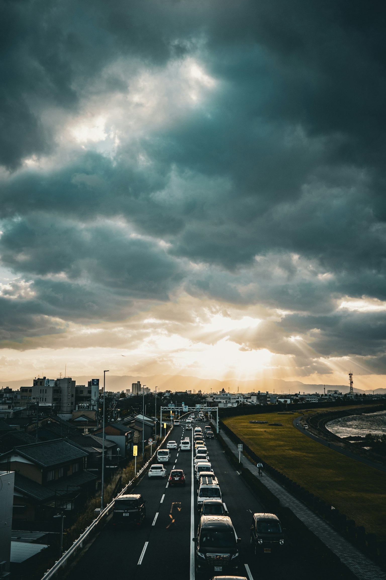 Autostrada urbana con traffico sotto nuvole drammatiche al tramonto