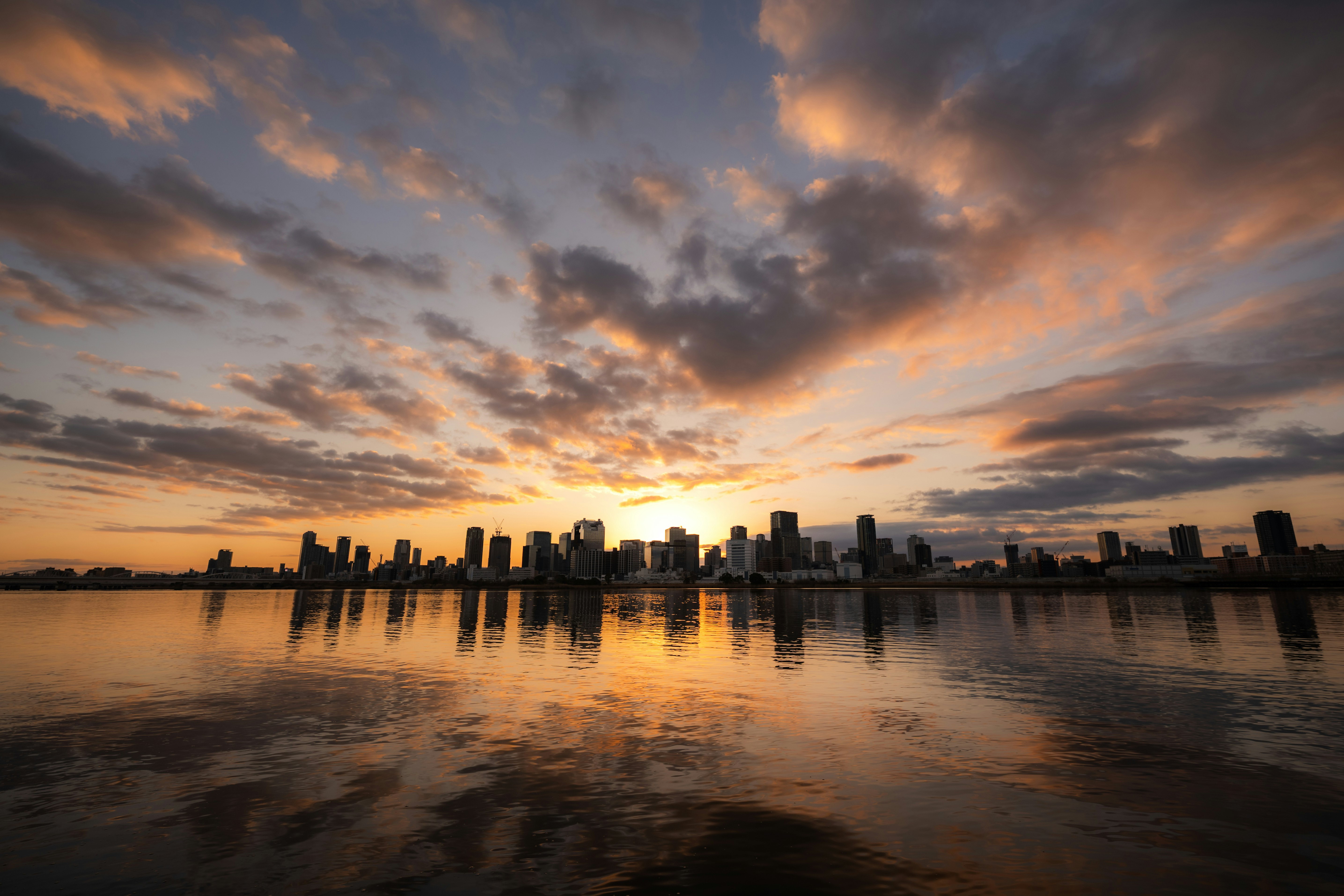 Stadtskyline bei Sonnenaufgang über einem Fluss