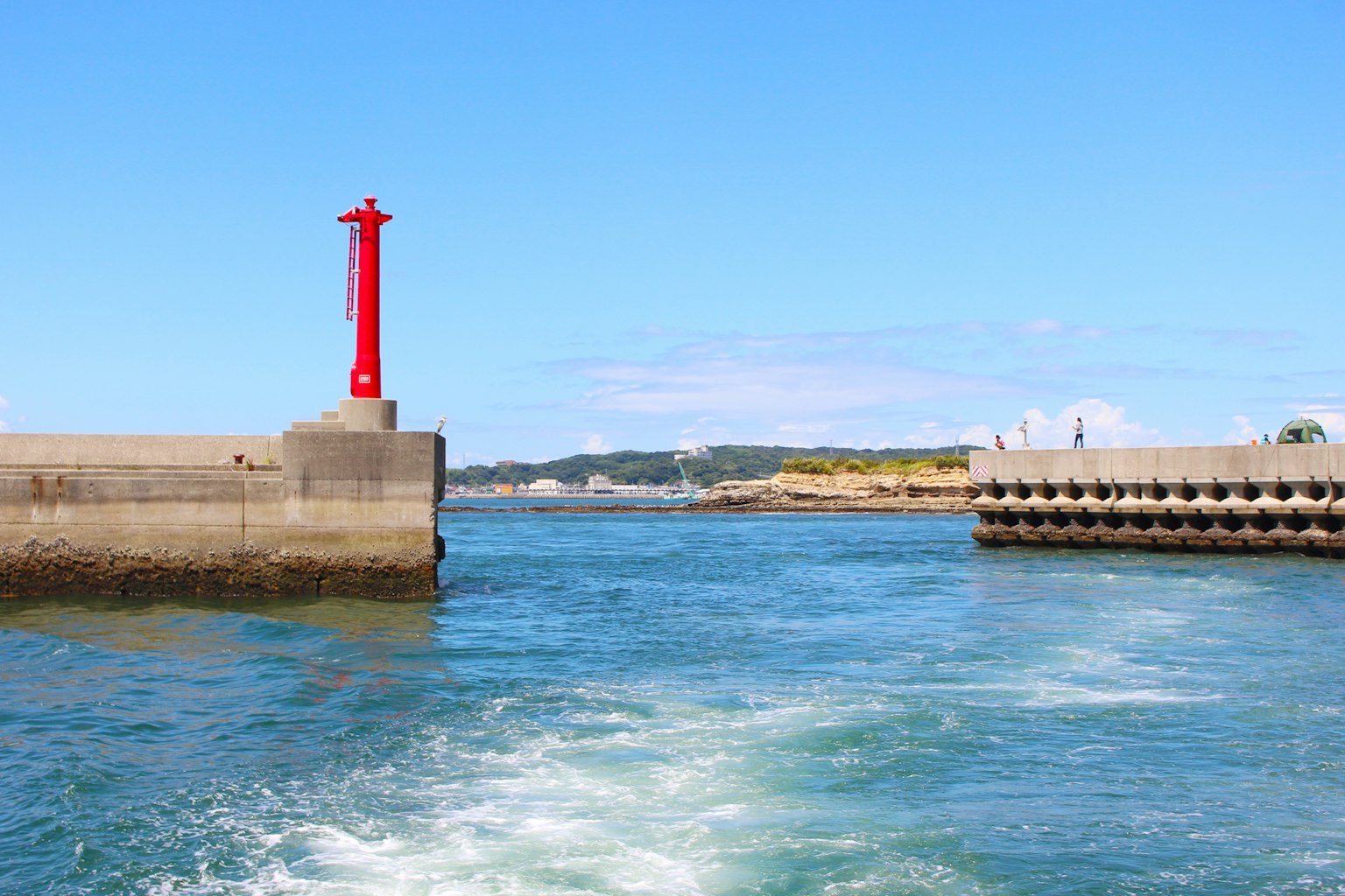 Vista escénica de un puerto con un faro rojo bajo un cielo azul