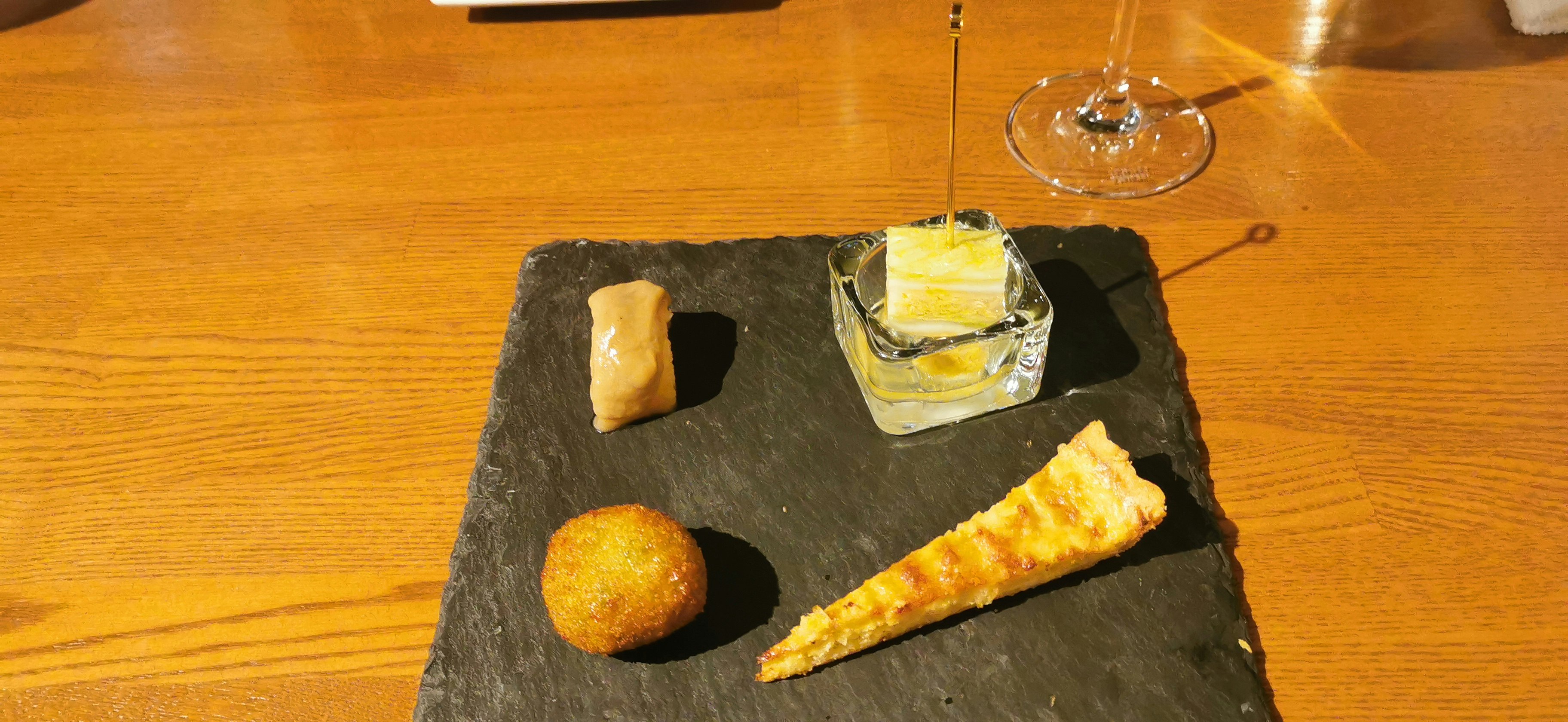黑色石板盘上的奶酪与面包，配一杯饮品的餐桌