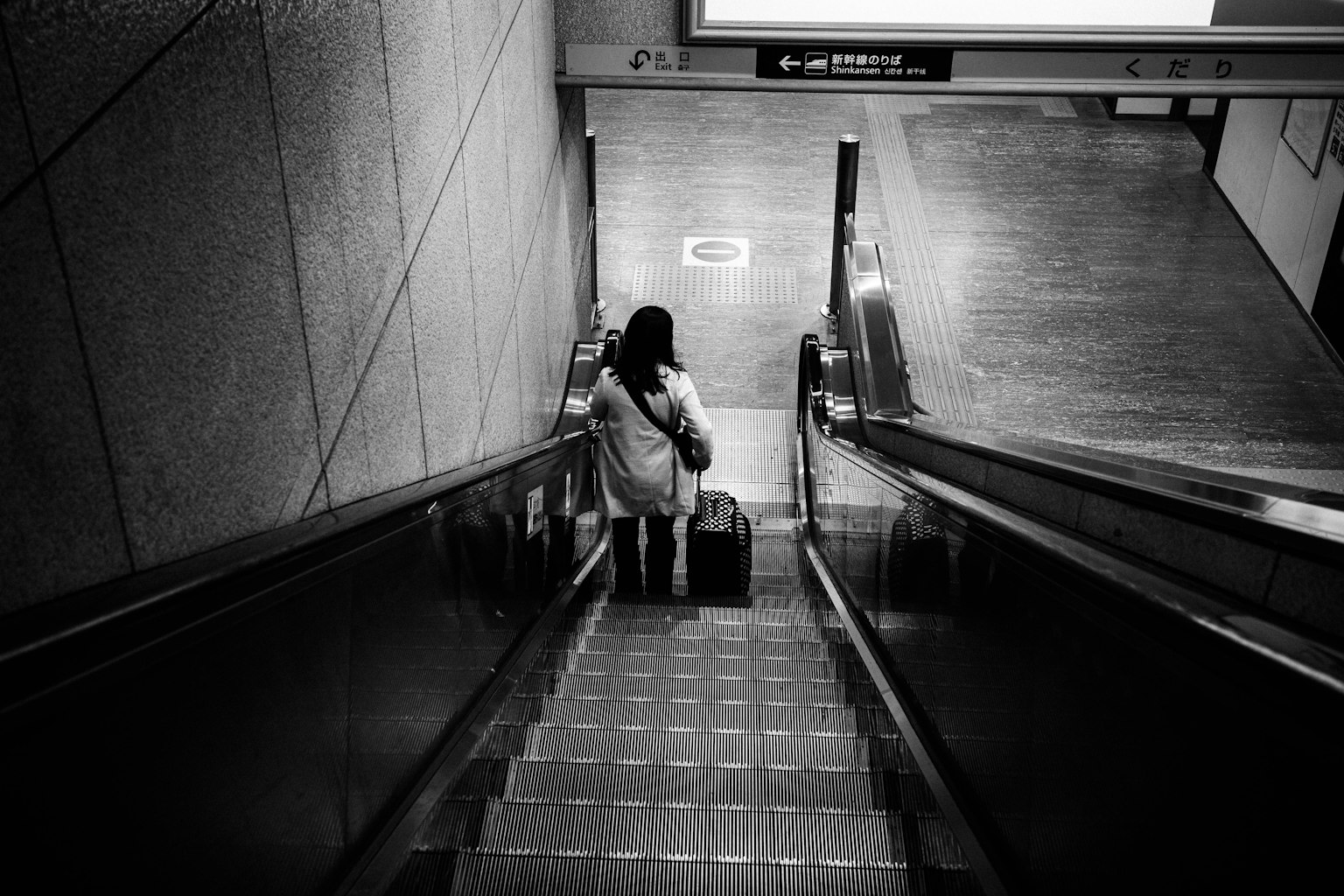 Woman descending stairs with suitcase black and white photo