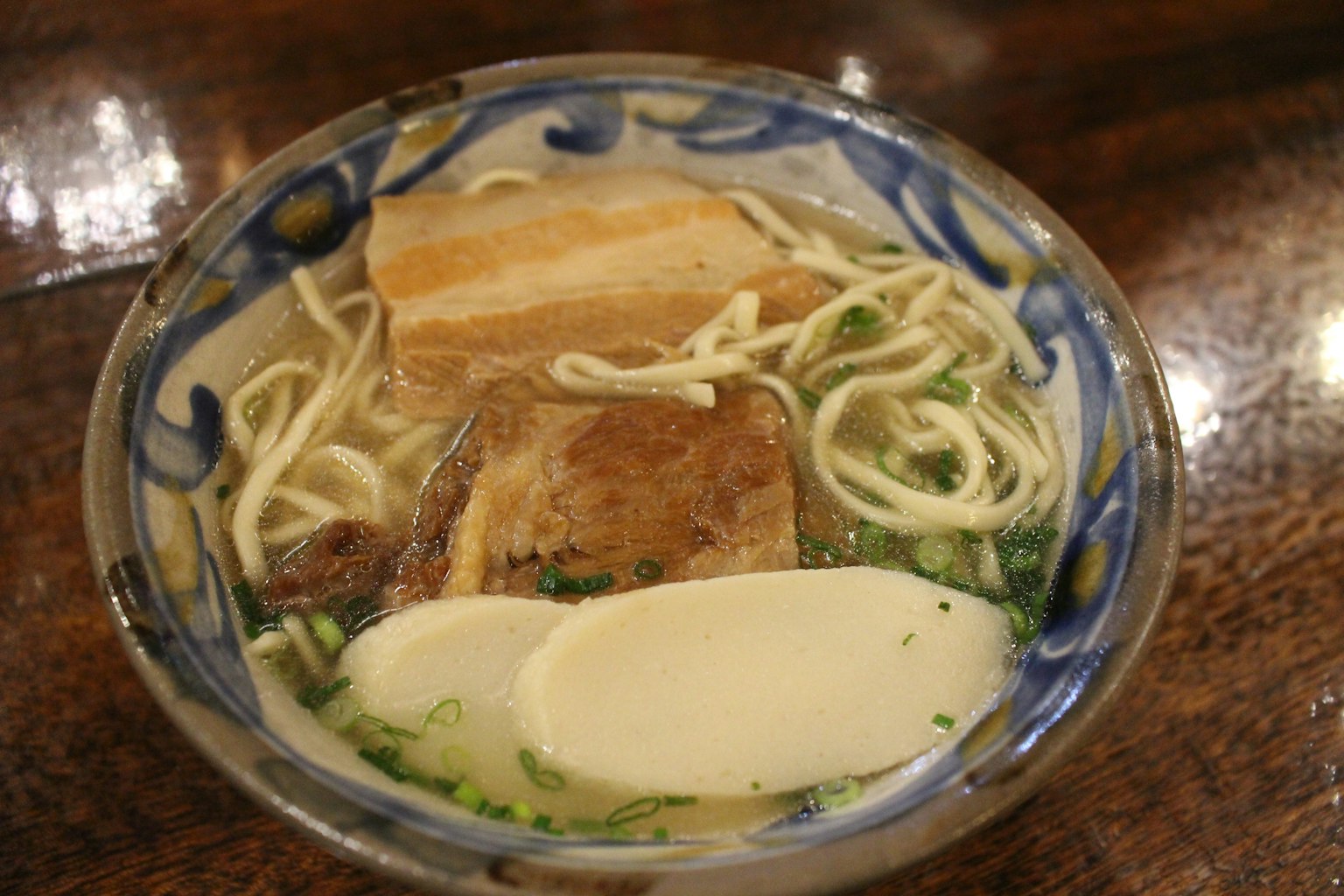 Un tazón de ramen con caldo, fideos, panceta, cebollín y mozzarella