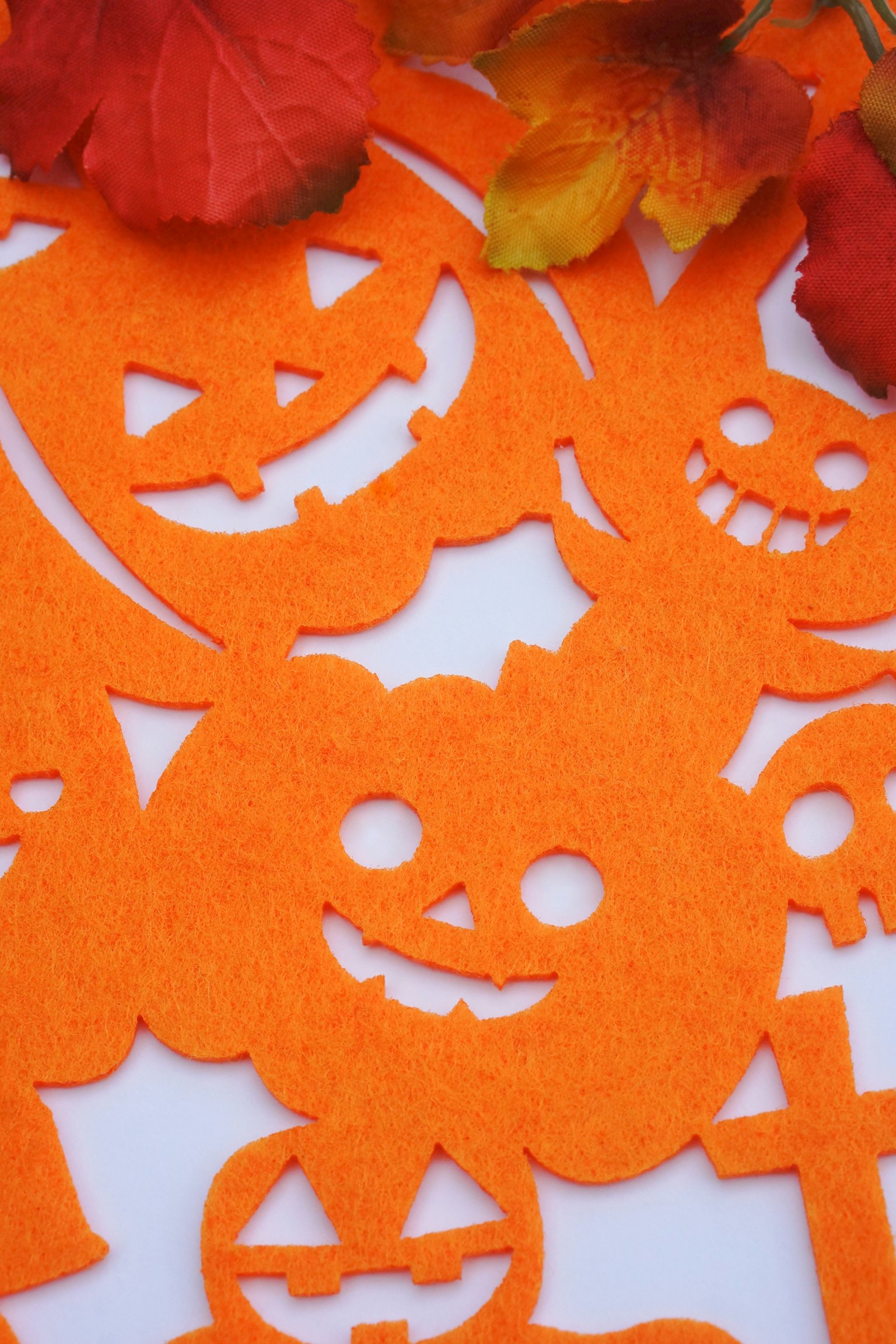 Orange Halloween-themed cutouts featuring smiling pumpkins on a white background