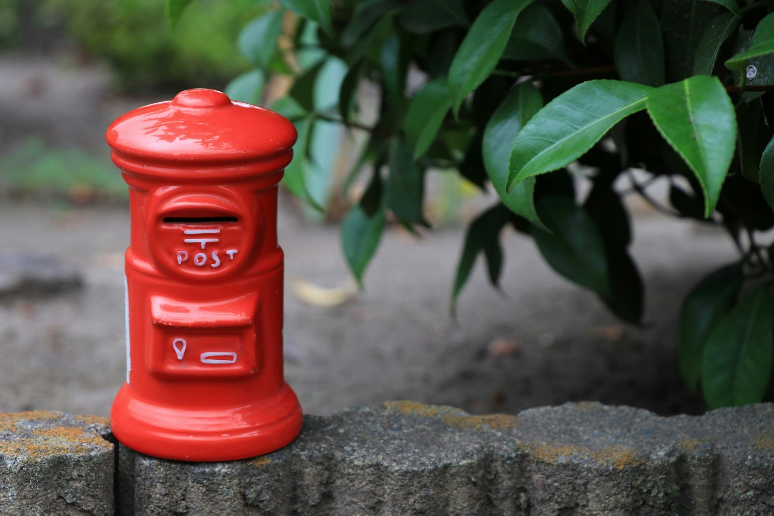 A red mailbox next to green foliage