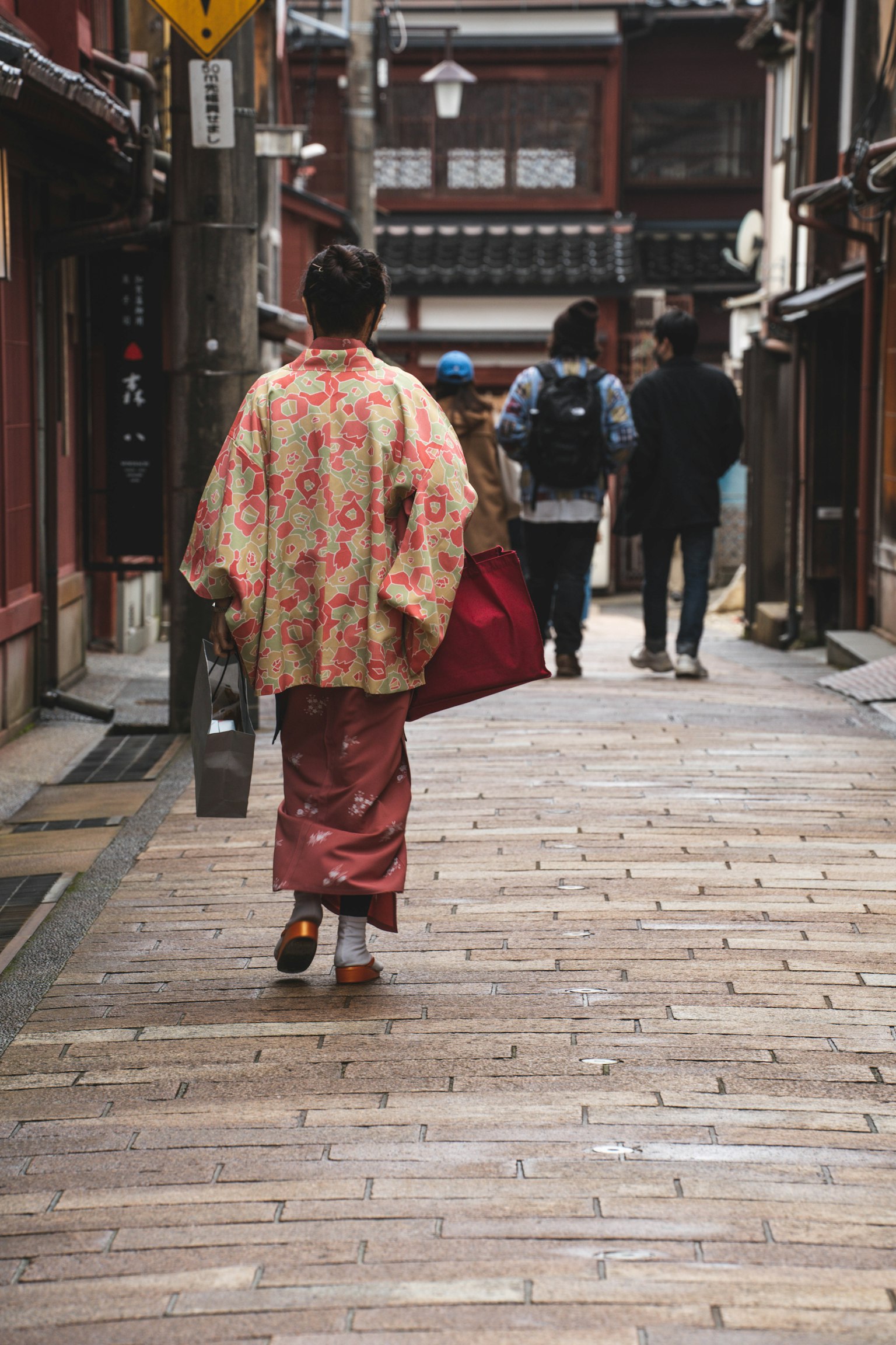 Wanita berpakaian kimono tradisional berjalan di jalan tua