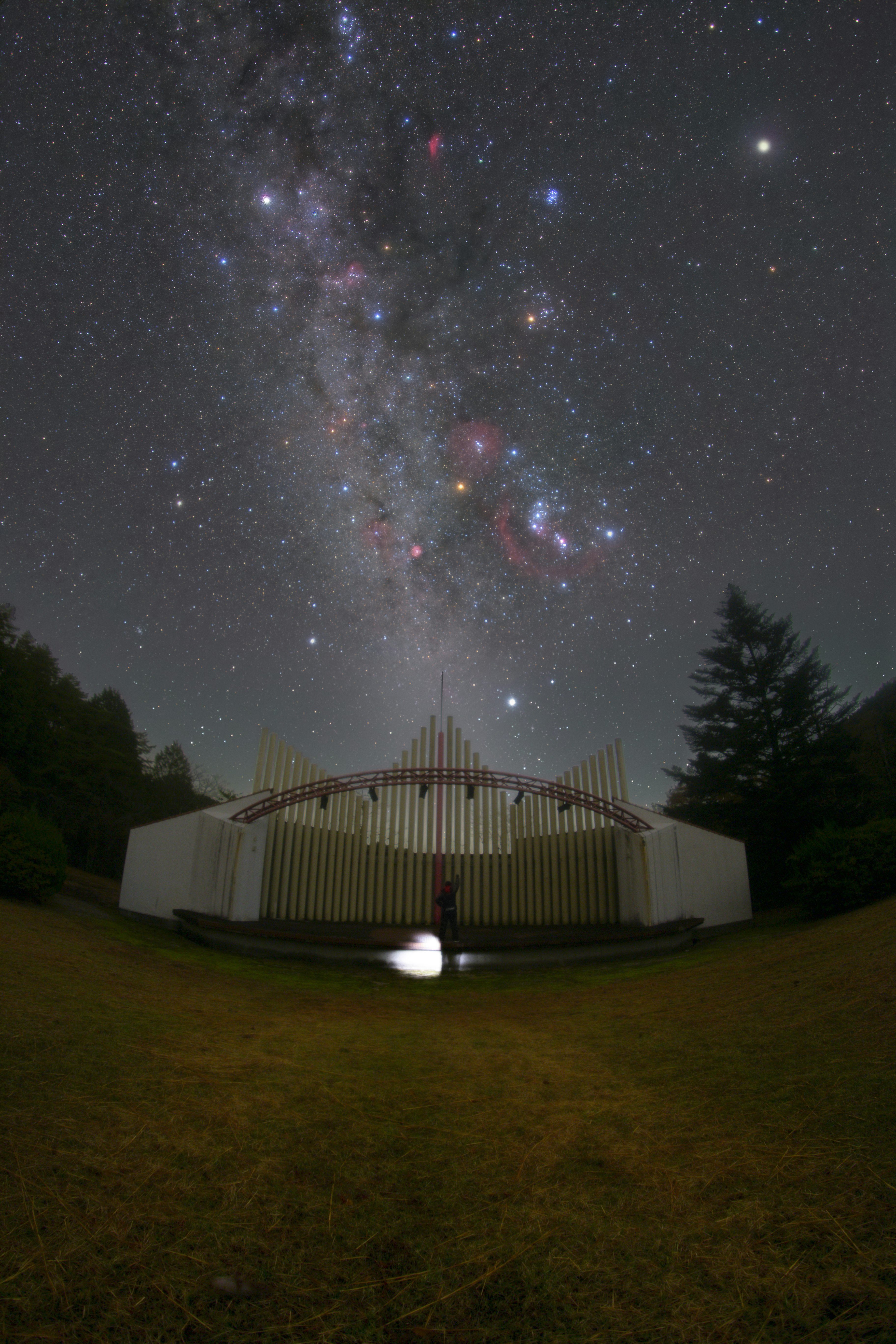 芝生の上にある円形の屋外ステージと満天の星空