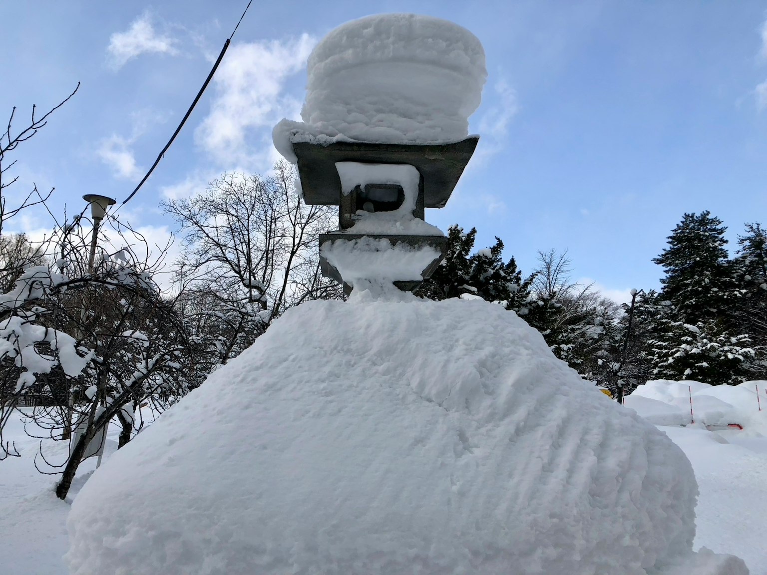 Steinlaterne mit Schnee und blauem Himmel